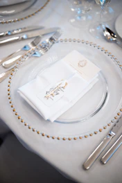 Elegant table setting with white napkins and gold trim.