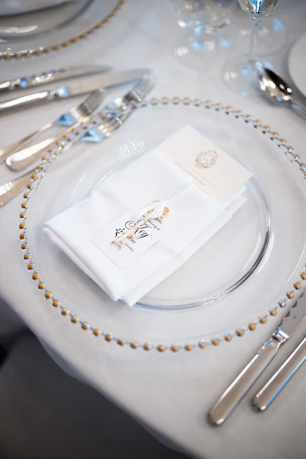 Elegant table setting with white napkins and gold trim.