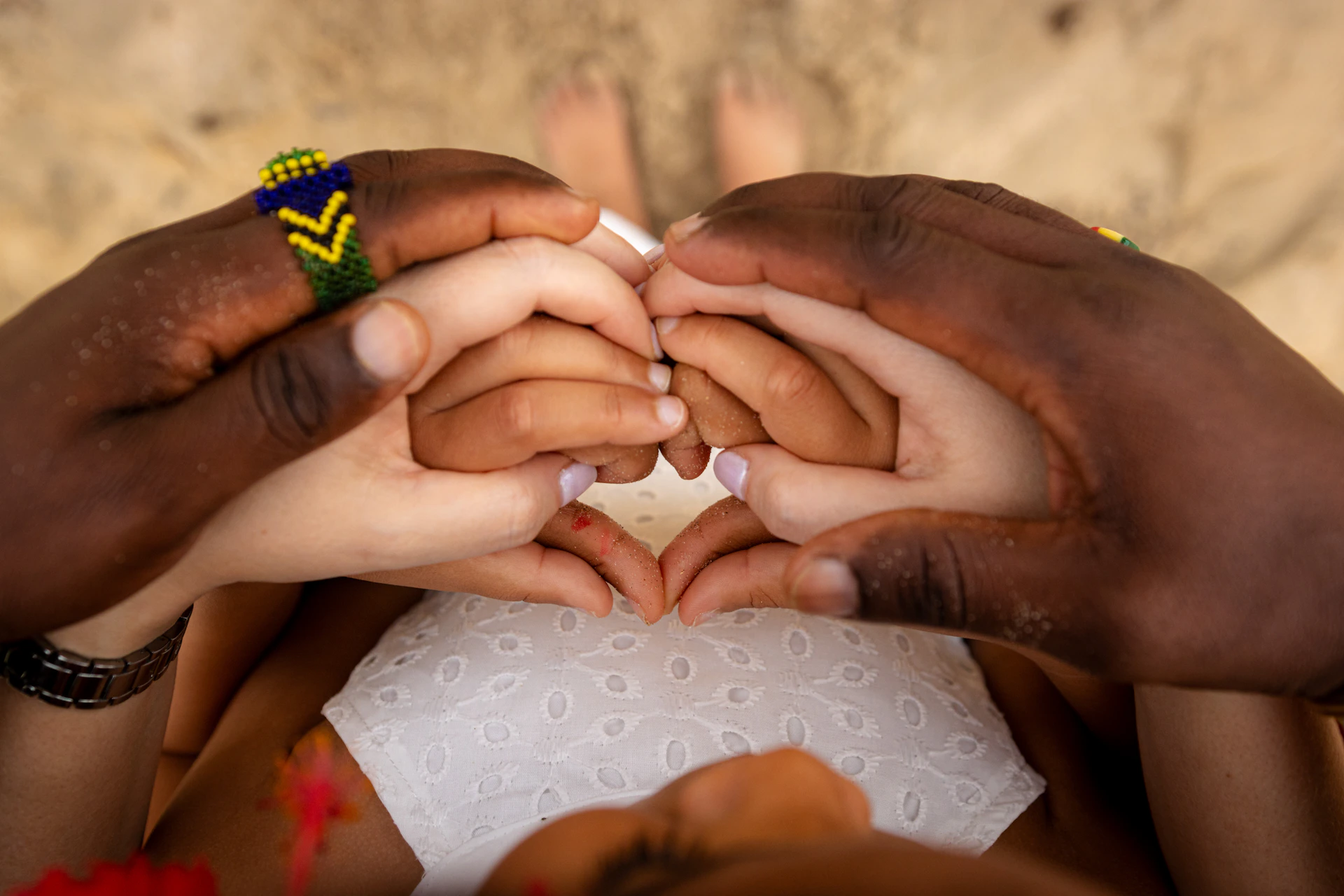 Hands forming a heart shape, diverse skin tones.