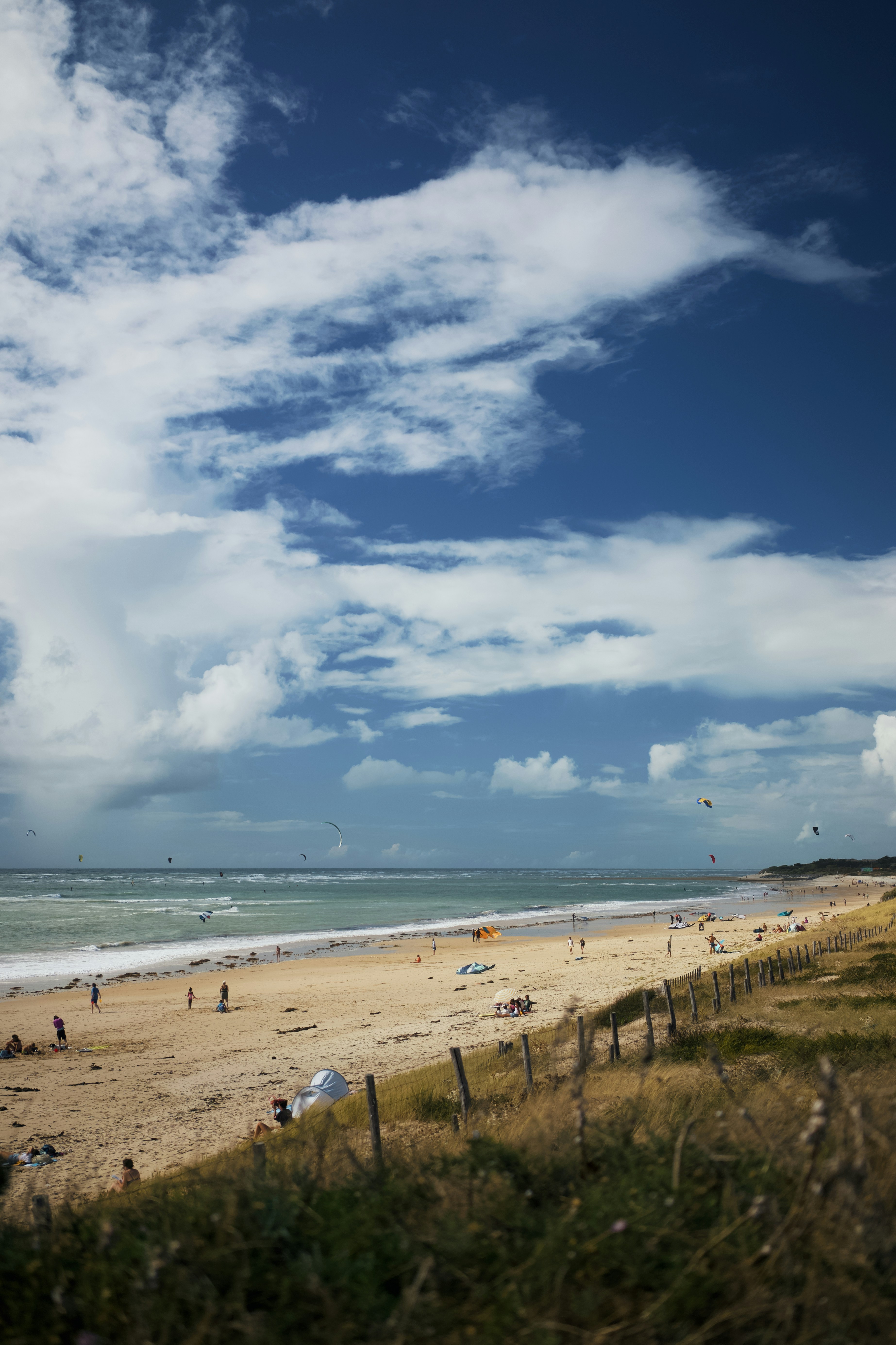 Strand mit Kitesurfern und fernem Unterholz an der Küste