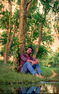 Man sitting under a tree by the water.