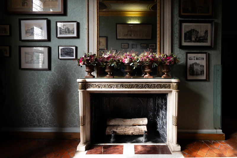 Ornate fireplace with floral arrangements and framed art
