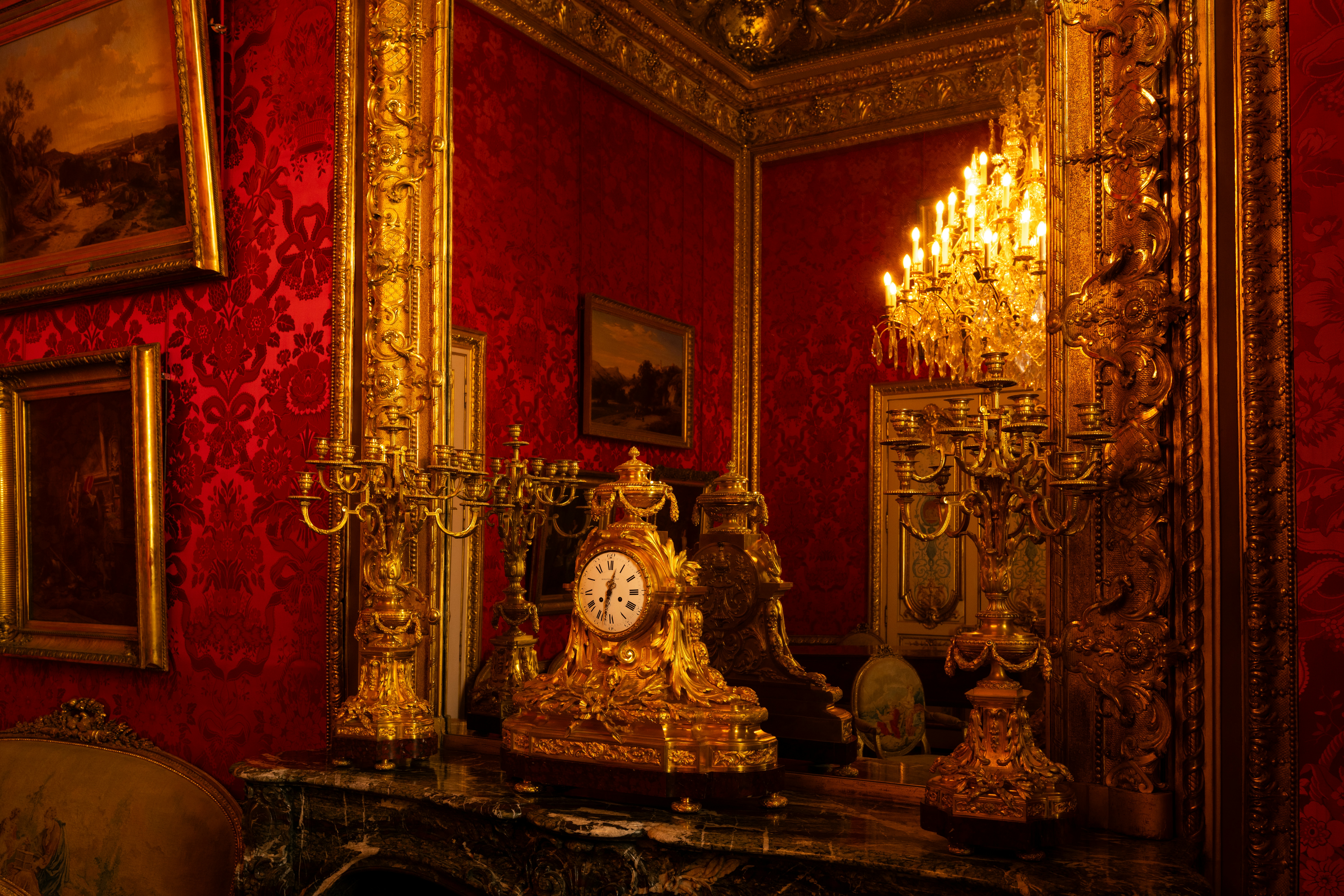 Ornate golden clock on a marble fireplace mantel.