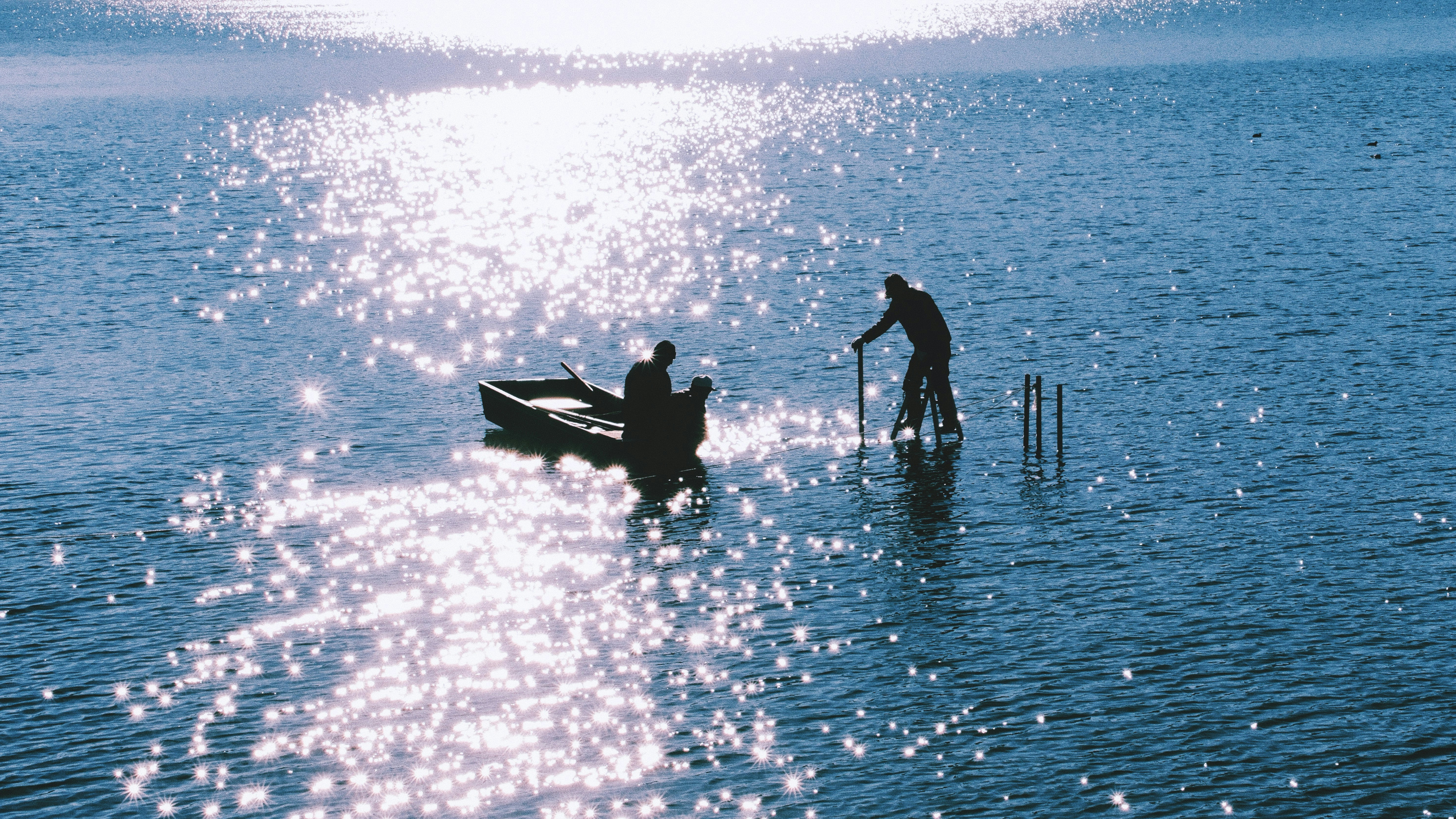 Silhouettes of people in a boat on sparkling water.