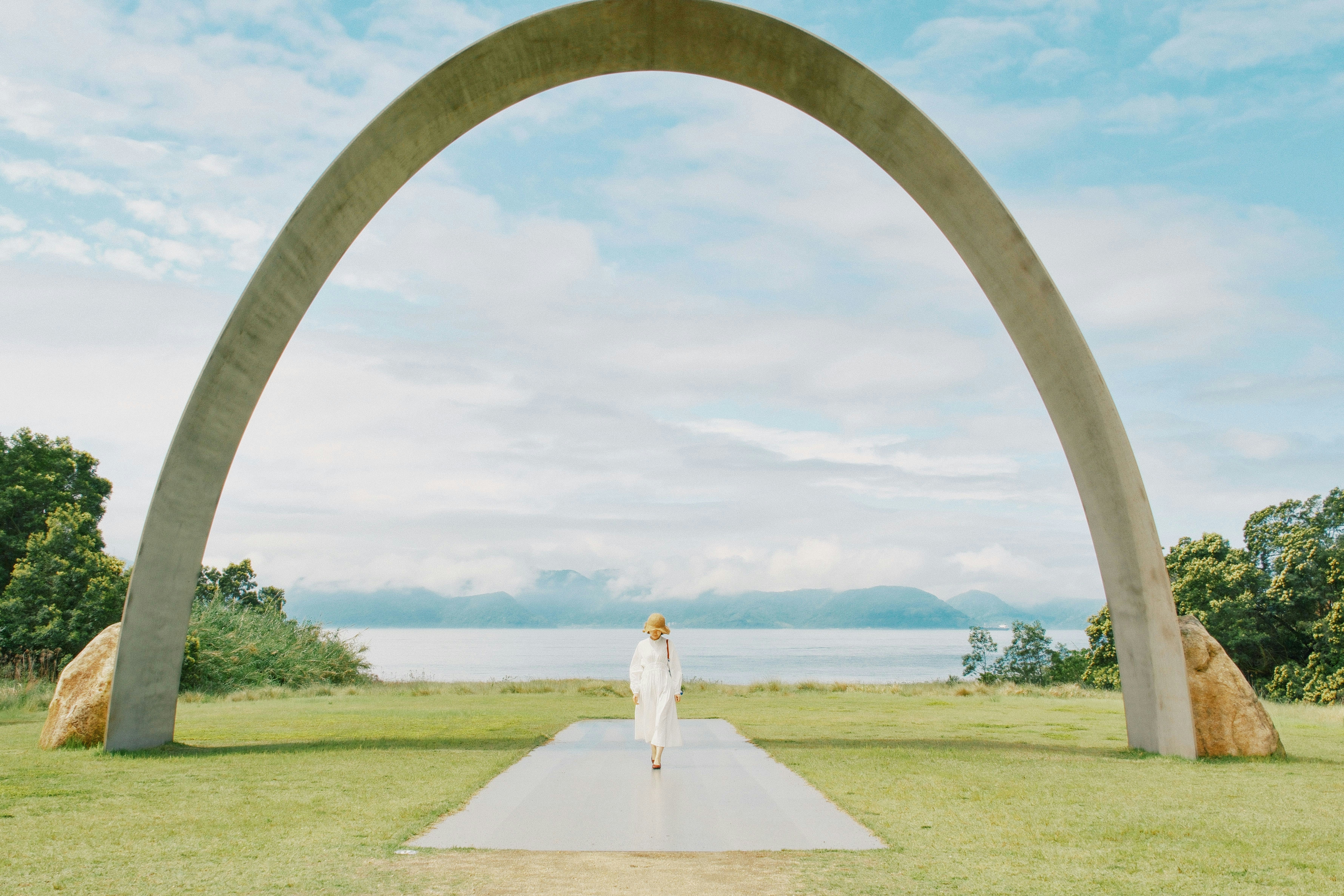 Woman walks through archway towards the ocean