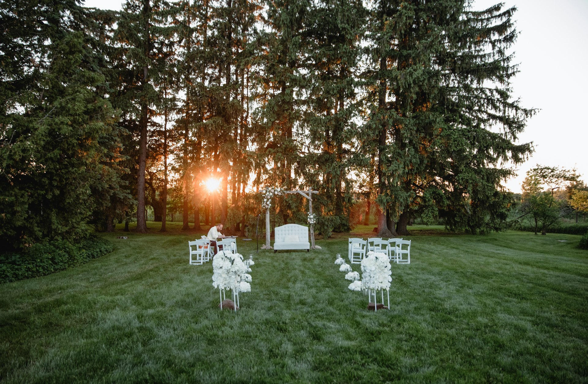 Outdoor wedding ceremony at a barn venue with sunset lighting