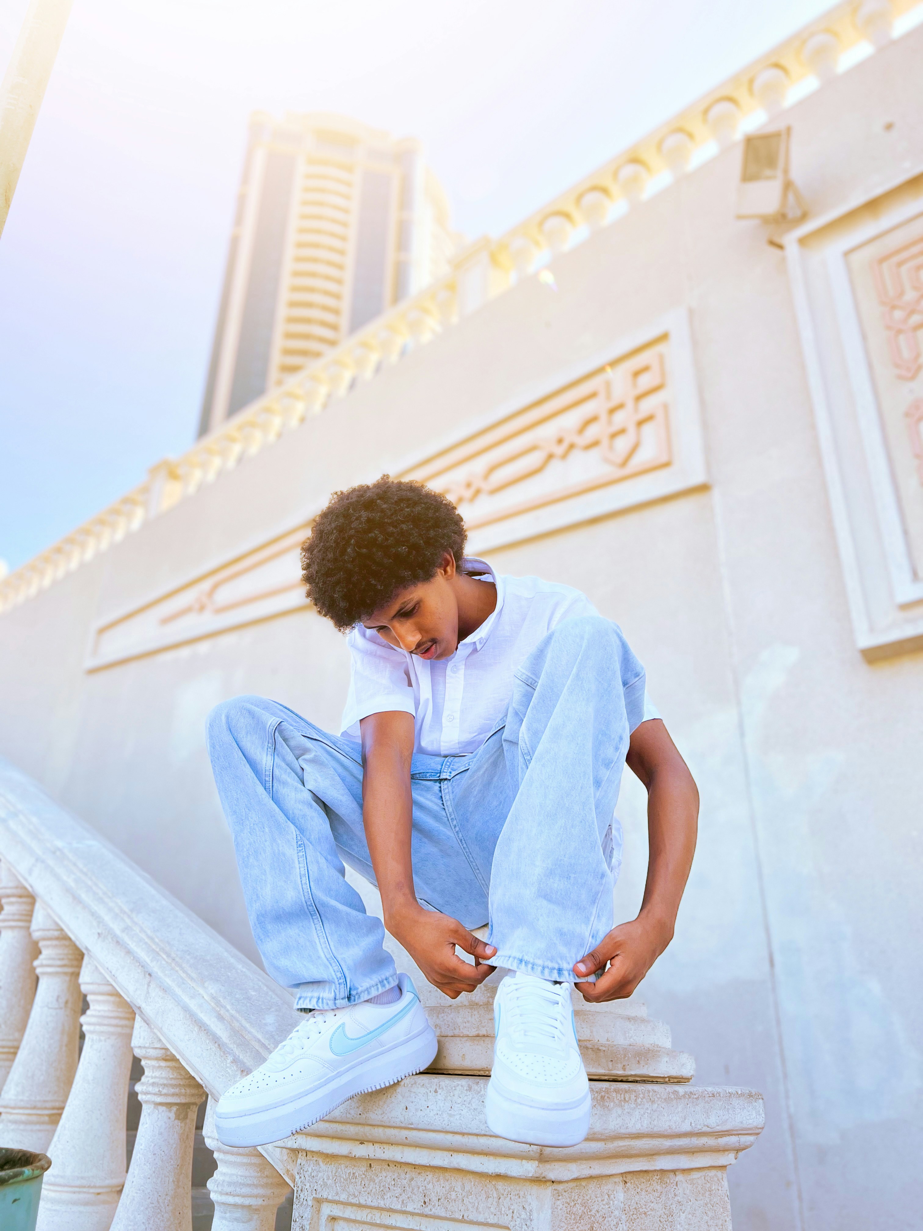 Young boy tying shoelaces on a sunny day.