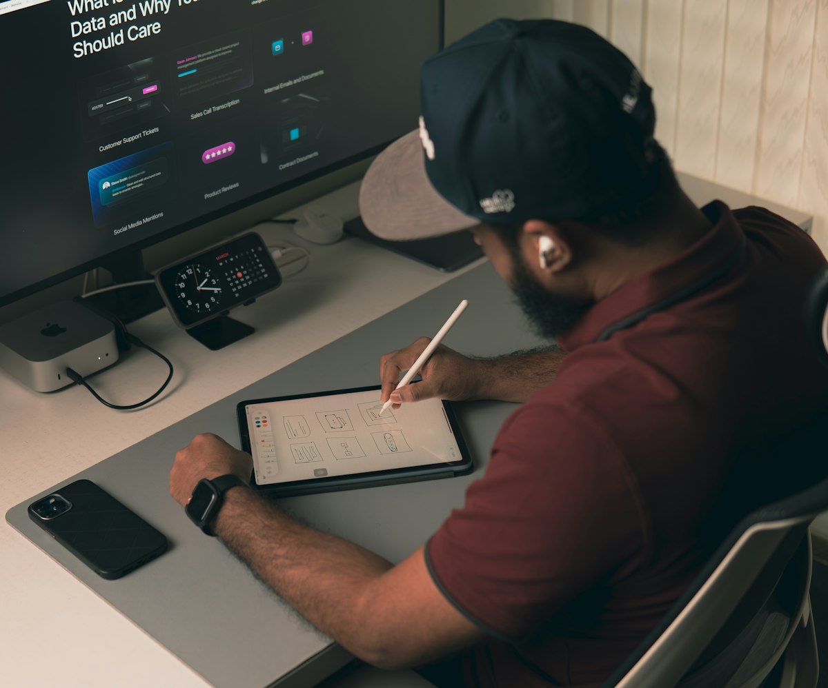 UX designer sketching wireframes at a desk with a computer and tablet