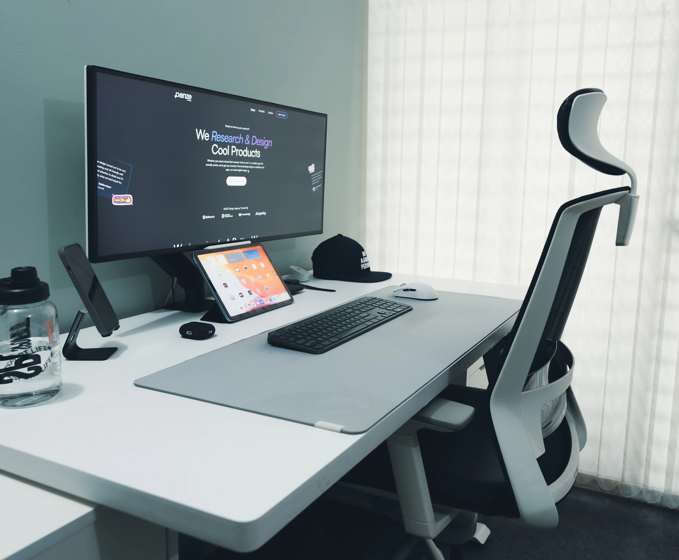 Organized modern desk setup with an ergonomic chair, computer monitor, keyboard, mouse, and device stand