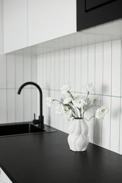White flowers in a textured vase on a black countertop