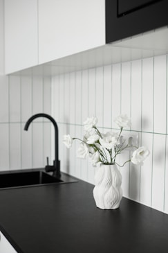 White flowers in a textured vase on a black countertop