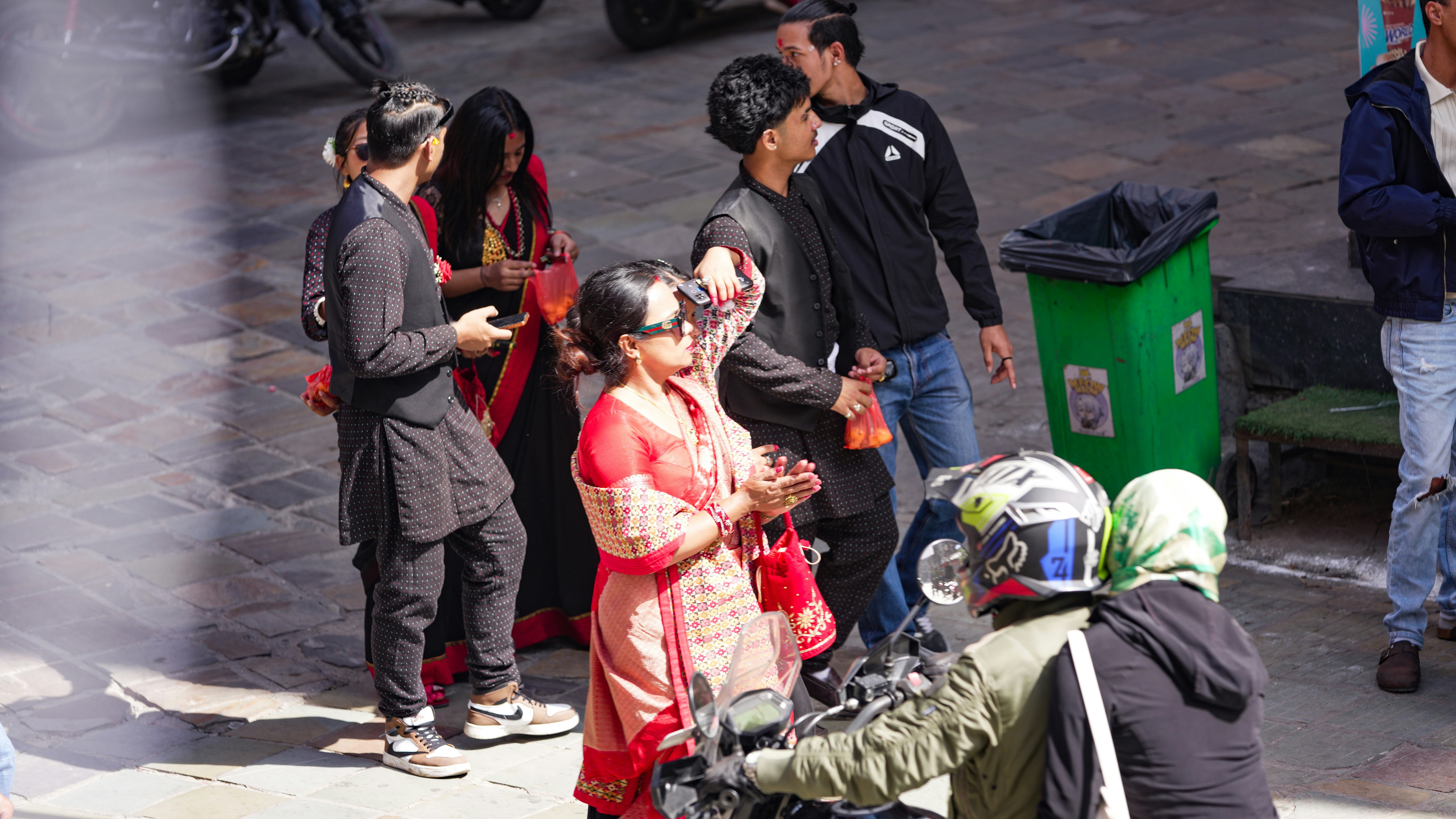 People gathered on a sunny street with motorcycles.