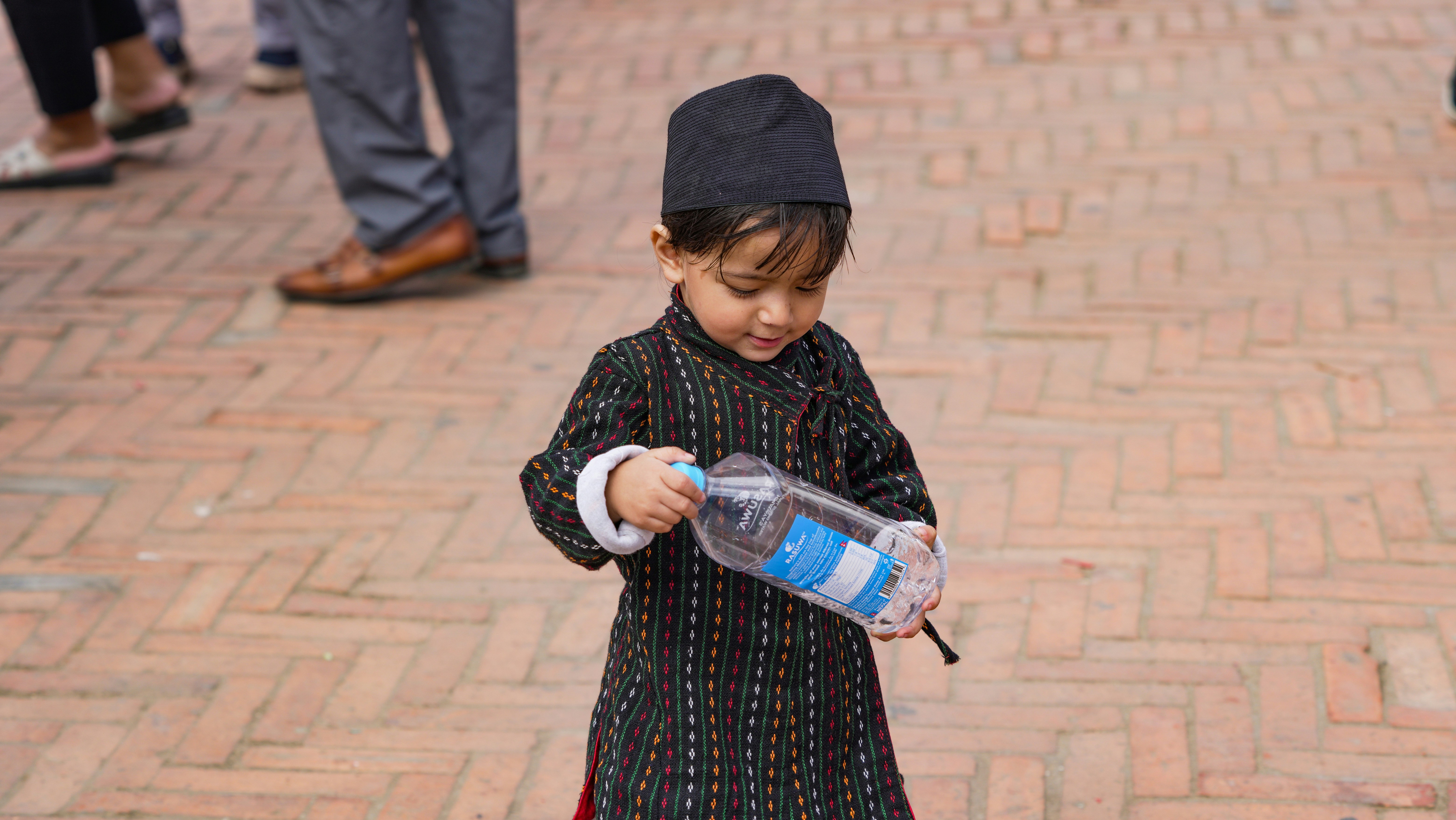Child in traditional clothing holding a bottle