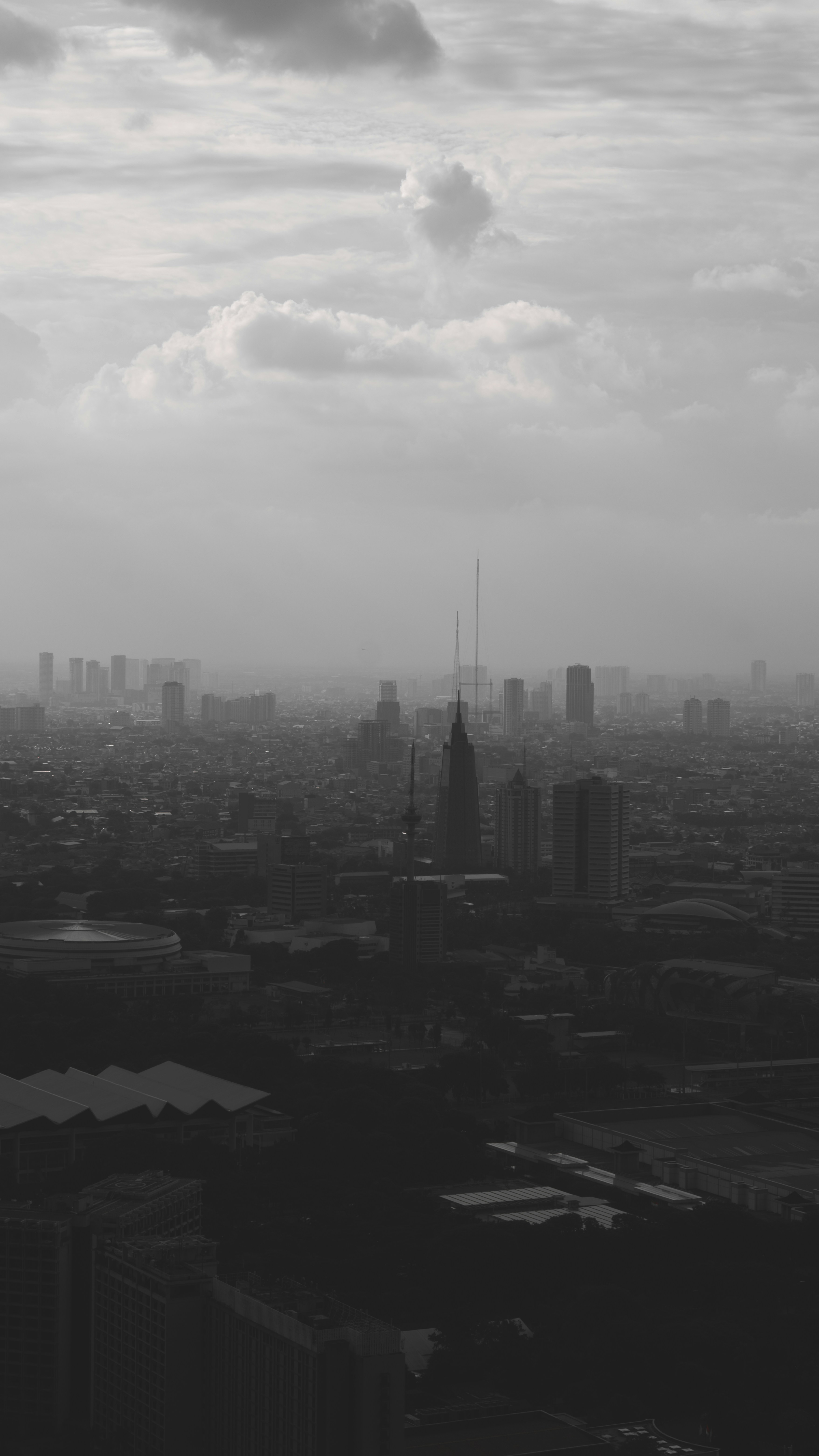 Misty city skyline with tall buildings under cloudy sky.