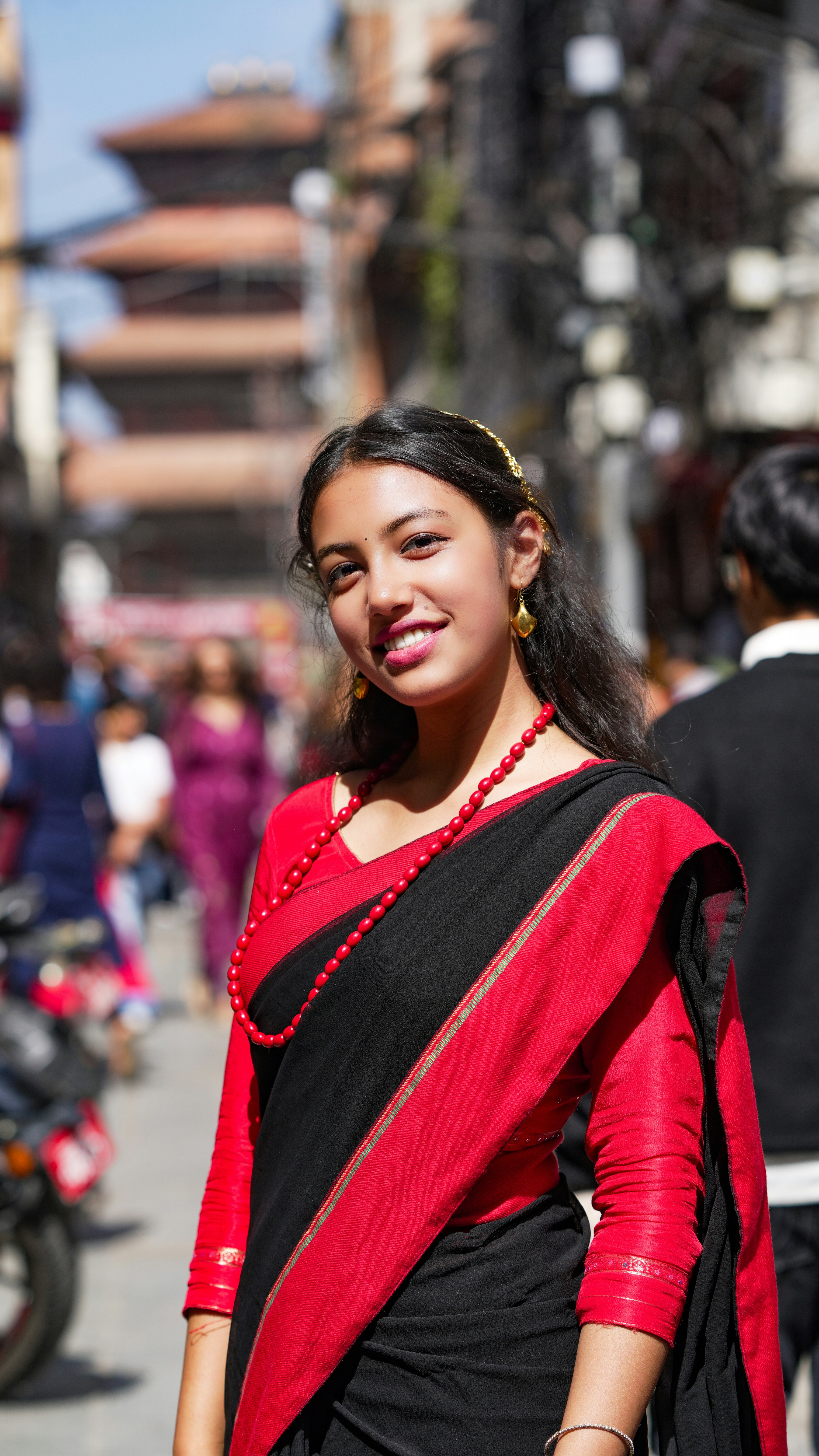 Young woman in traditional red and black clothing smiles.