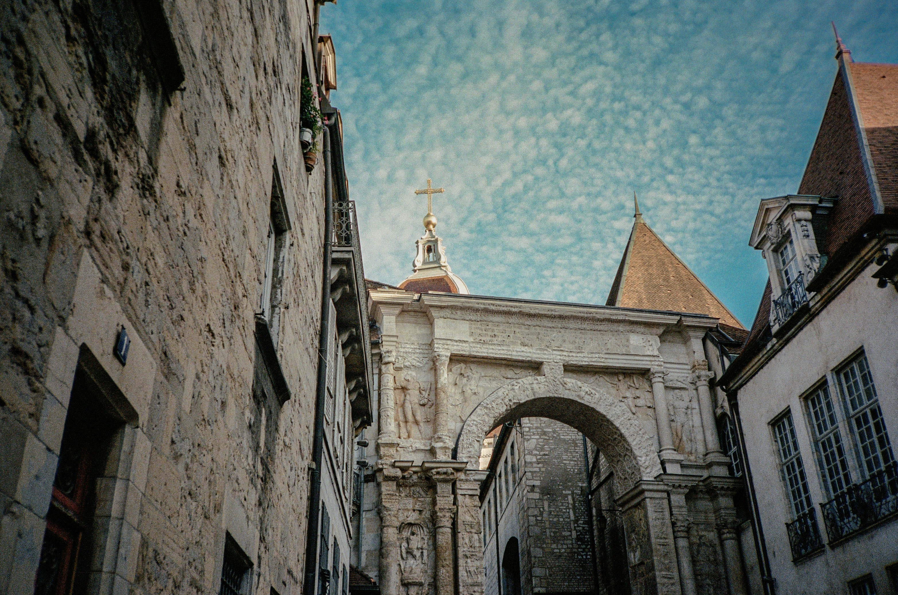 Stone archway and buildings under a dramatic sky