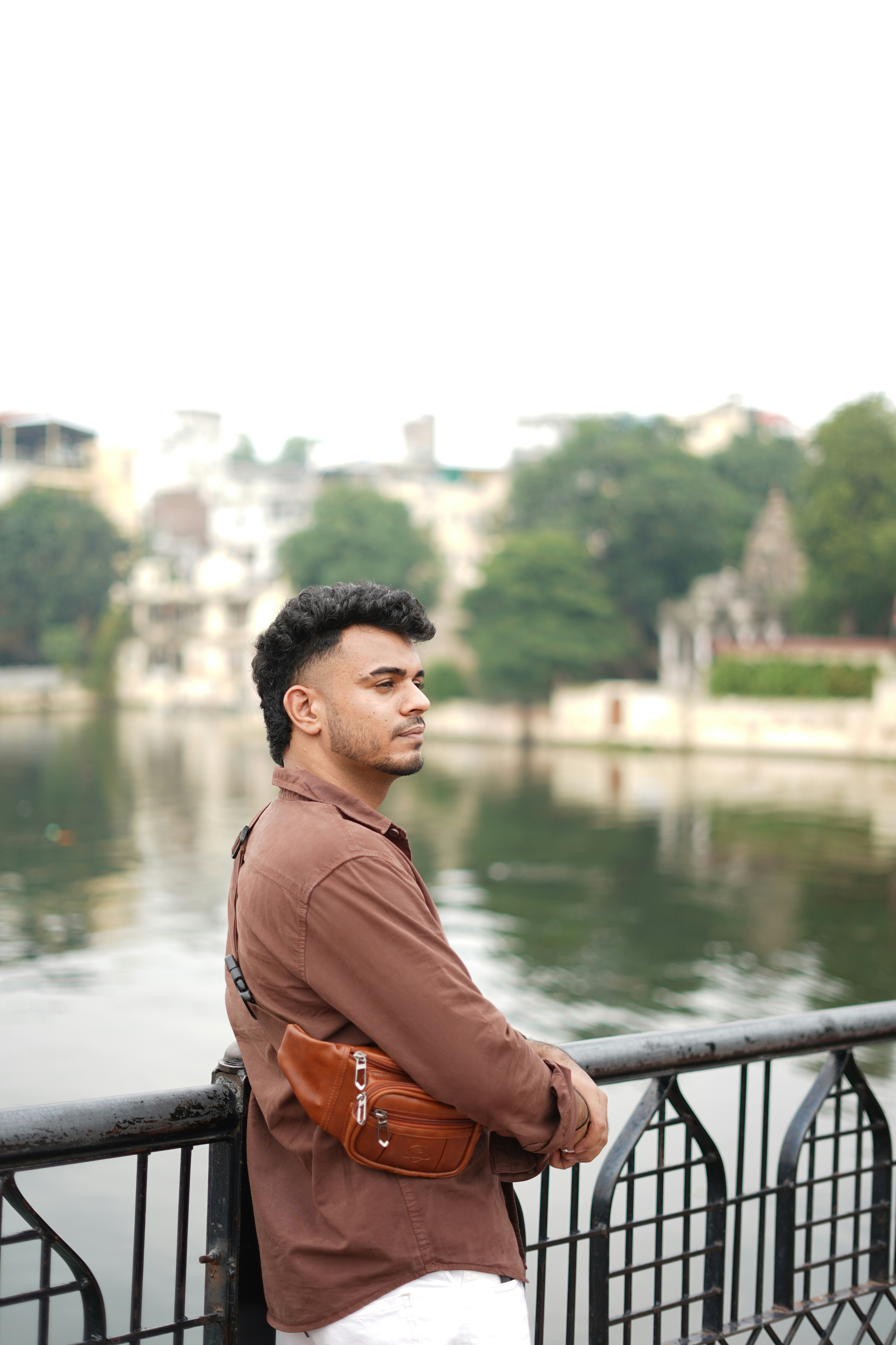 Man leaning on railing by a calm lake