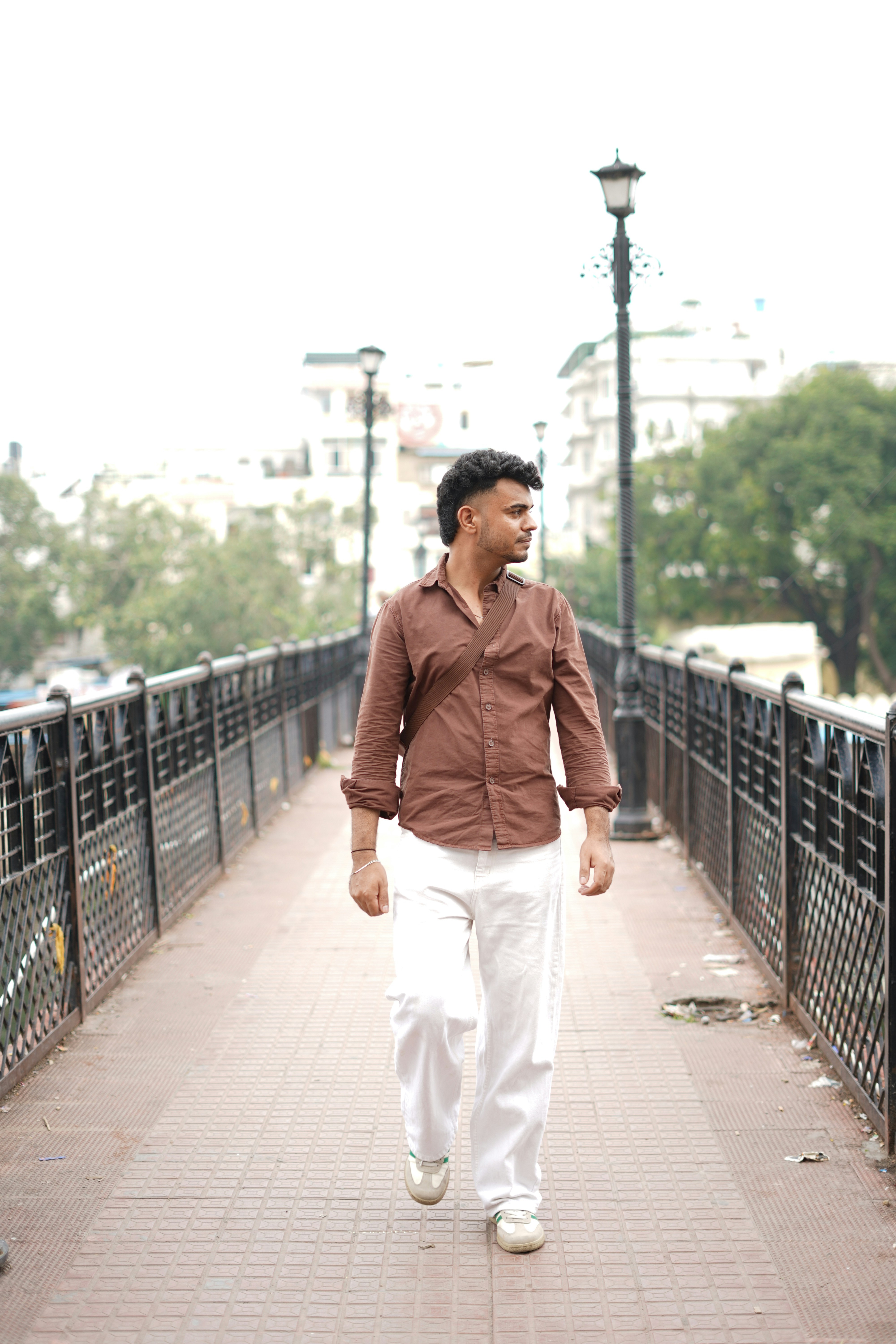 Hombre caminando sobre un puente con edificios detrás.