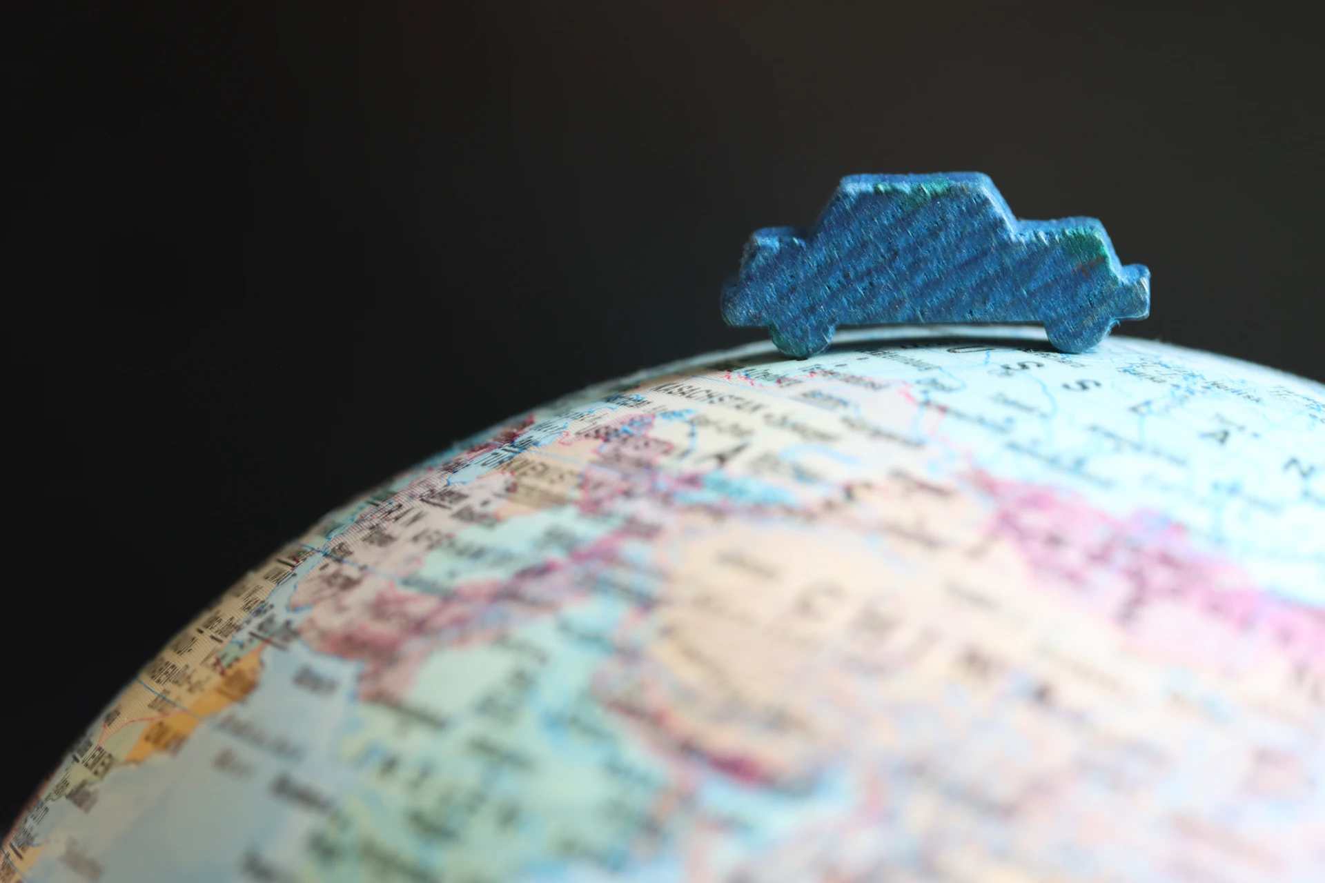 Blue toy car on top of a globe