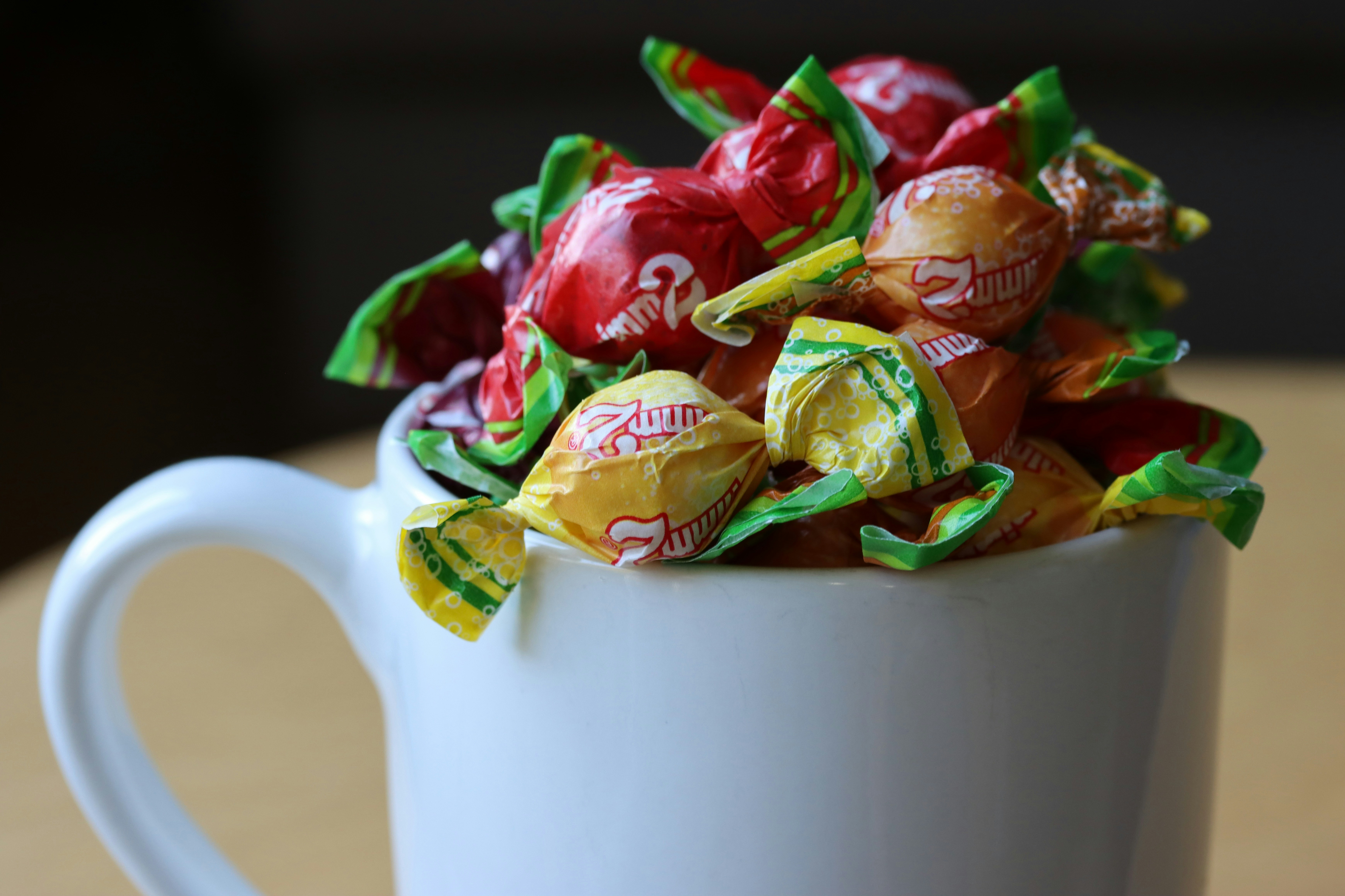 A white mug filled with colorful wrapped candies