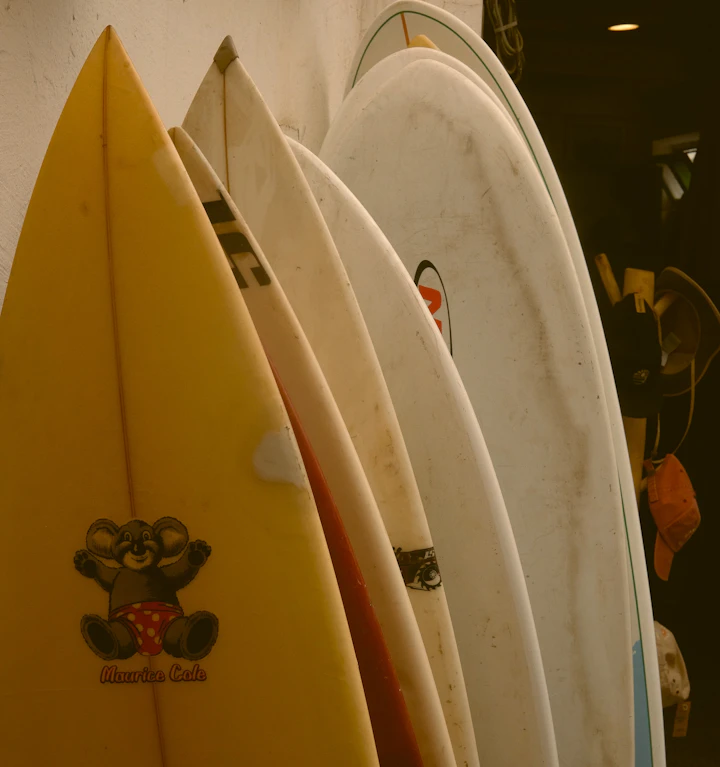 A row of upright surfboards racked in a shop, shortboards in the foreground