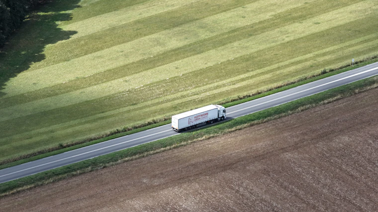 White long-haul truck driving on a road through open fields