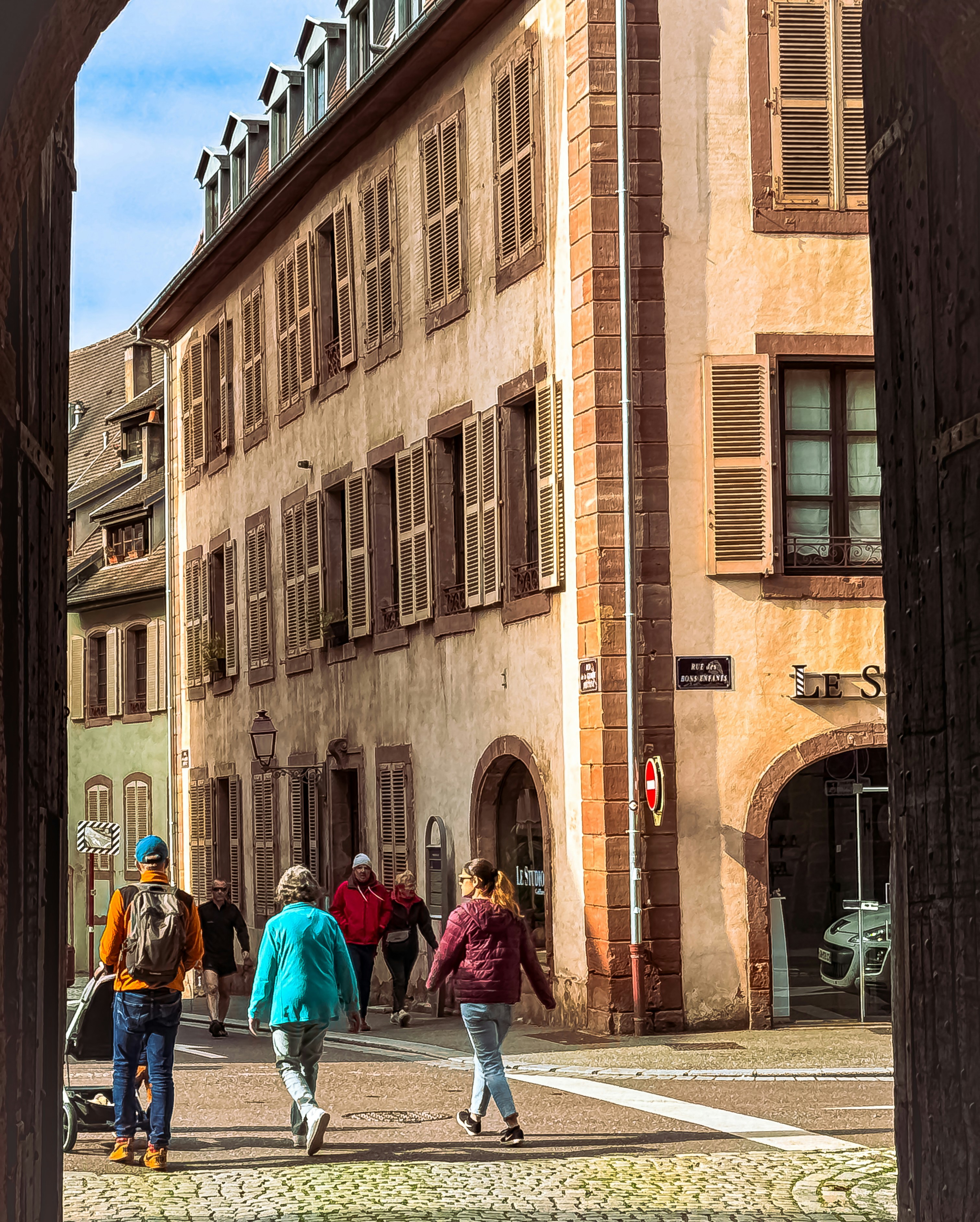 People walking down a european street with buildings.