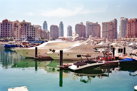 Luxury yachts docked in a modern harbor with city skyline.