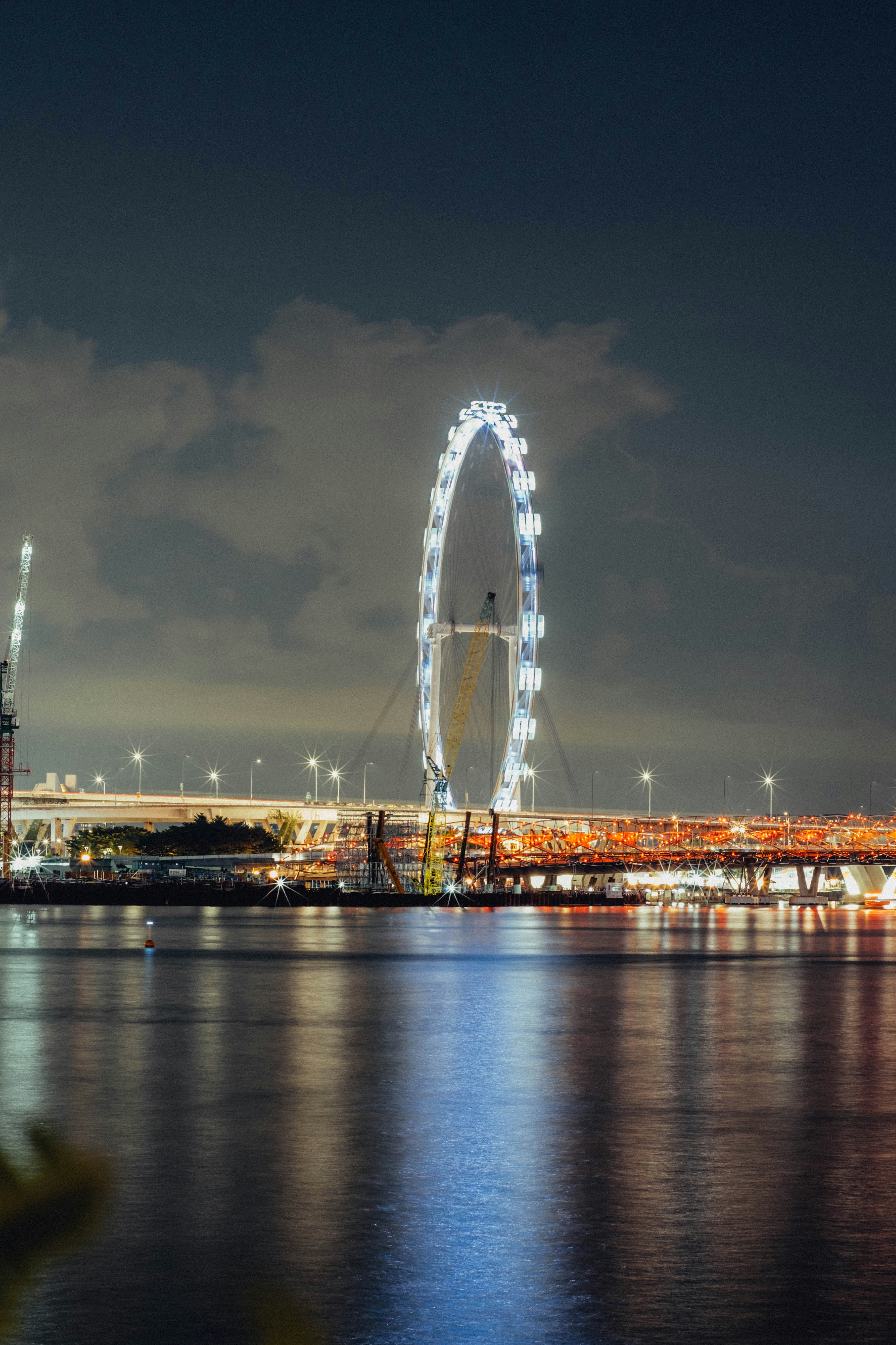 Riesiges Riesenrad, das nachts über Wasser beleuchtet wird