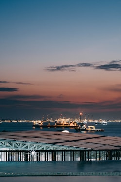 Ships on the water at dusk with city lights.