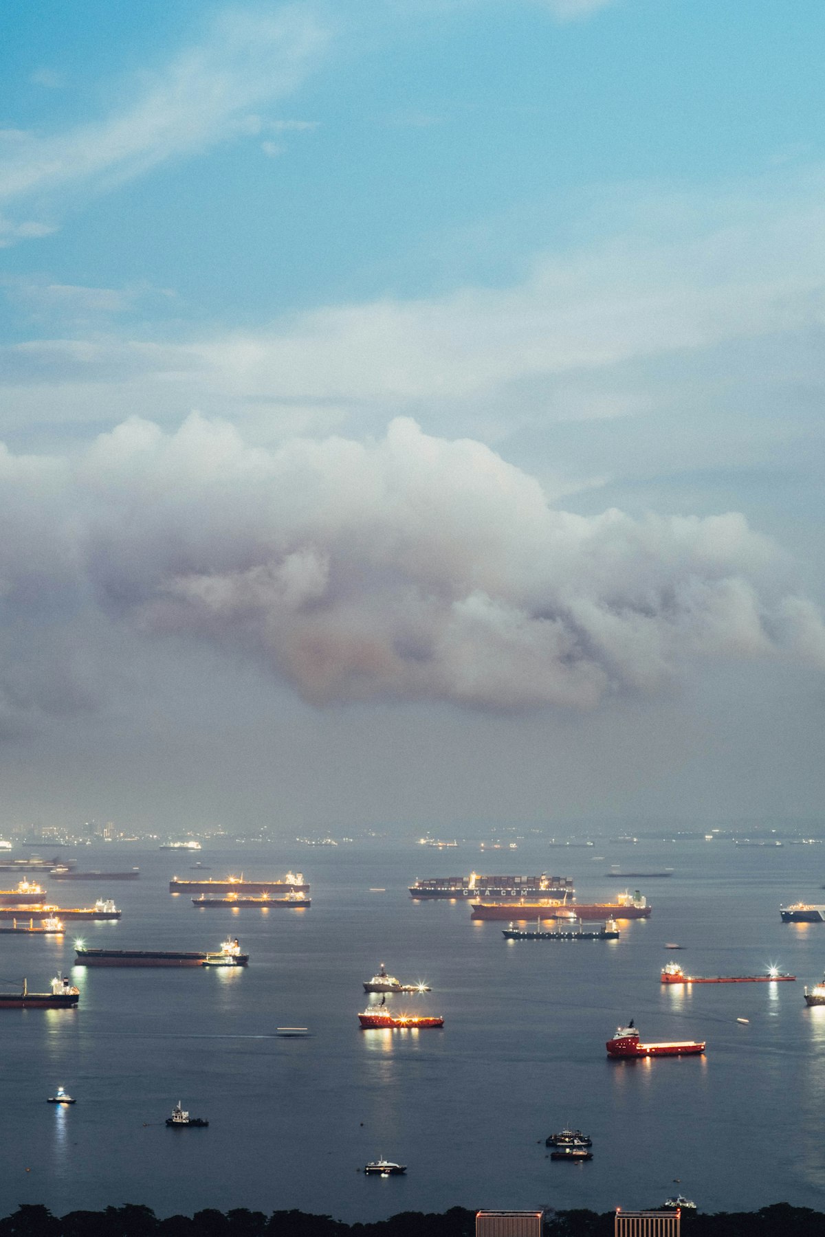 Cargo ships anchored in a bay at dusk, representing global maritime trade and the Strait of Hormuz oil chokepoint