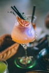 A refreshing cocktail with orange garnish and herbs