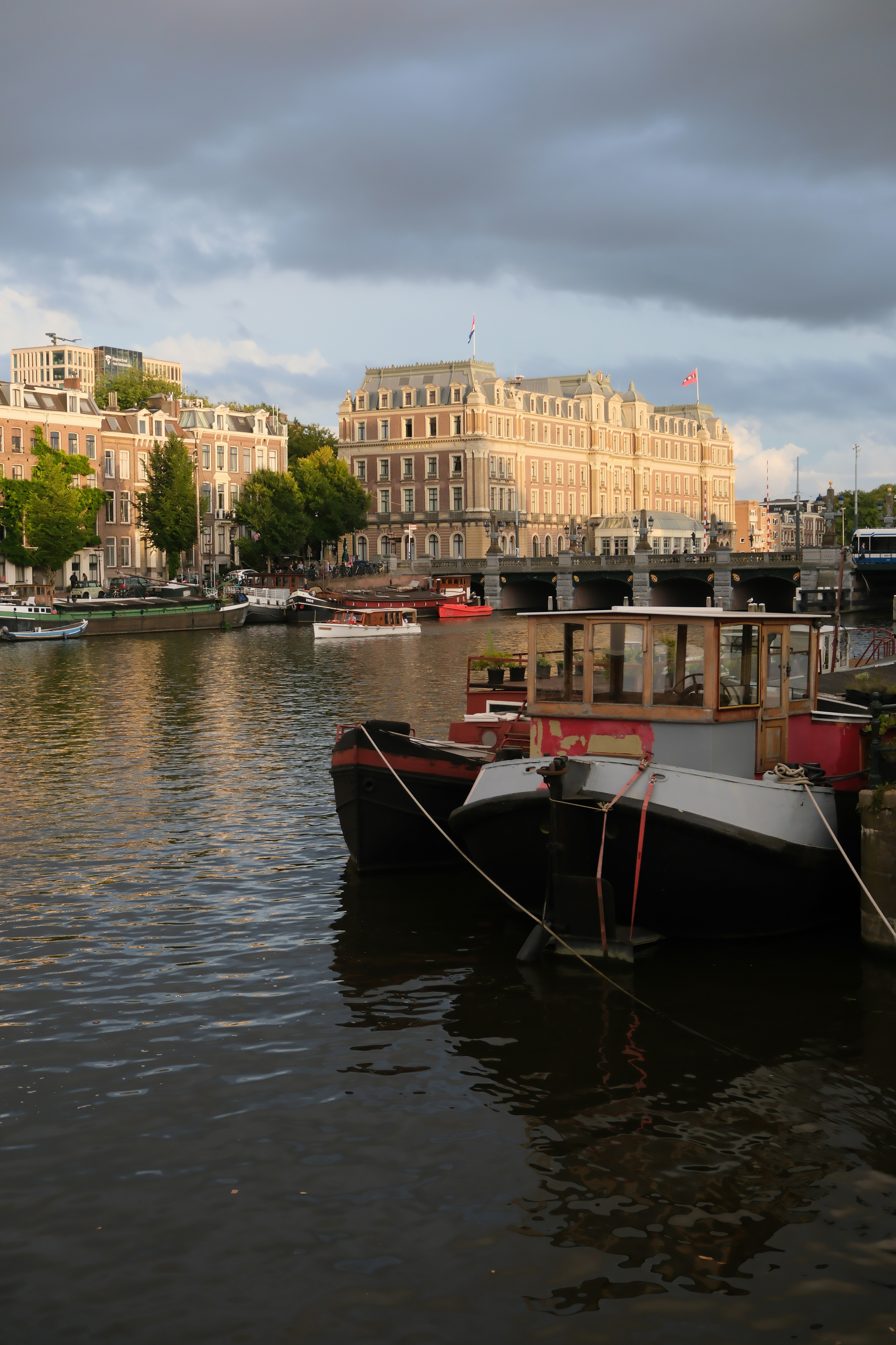 Boats on a canal with historic buildings in amsterdam. - boats-on-a-canal-with-historic-buildings-in-amsterdam-WapYk5NuUCo