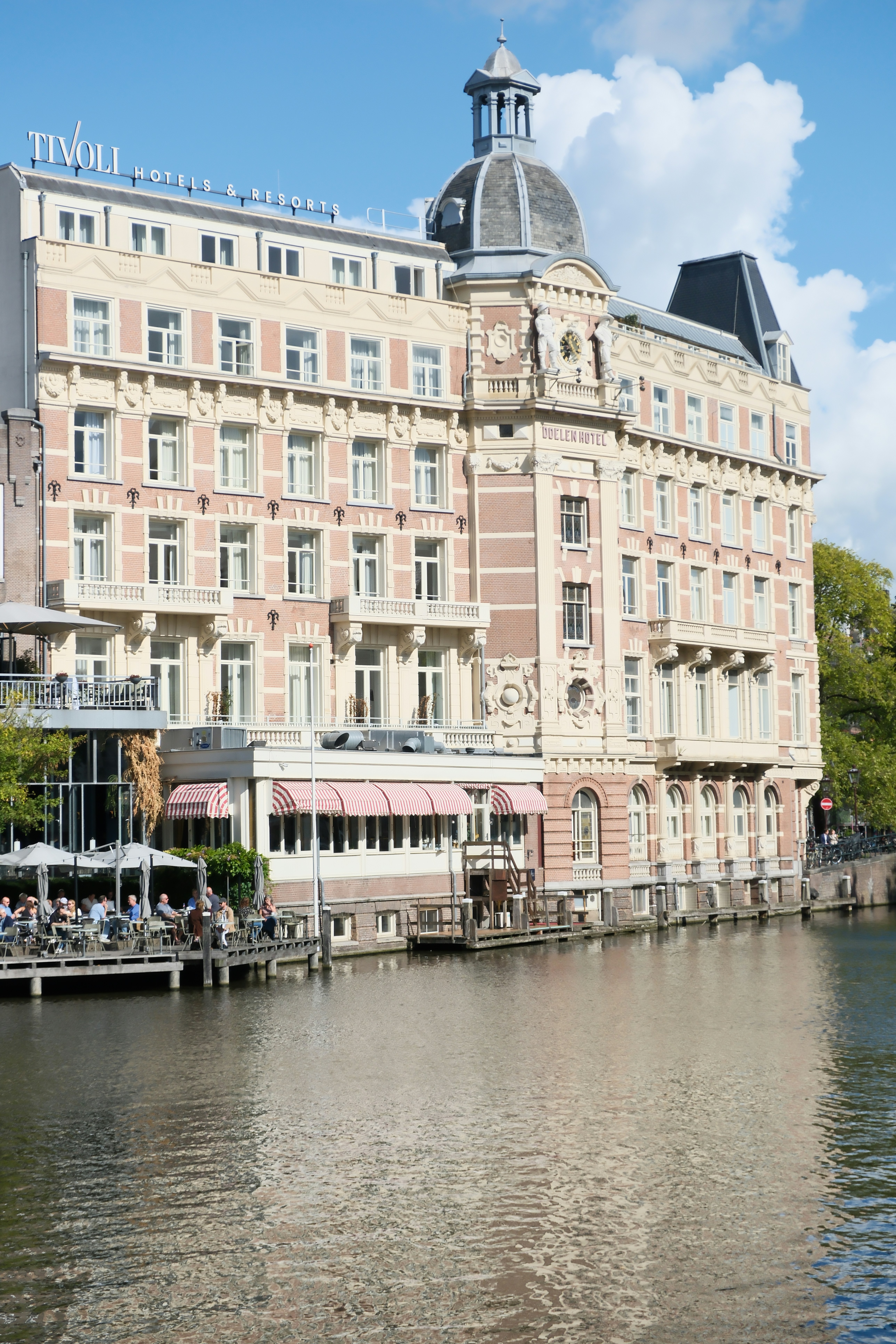 Grand hotel building on canal with outdoor seating - grand-hotel-building-on-canal-with-outdoor-seating-b2jsM1baV_M