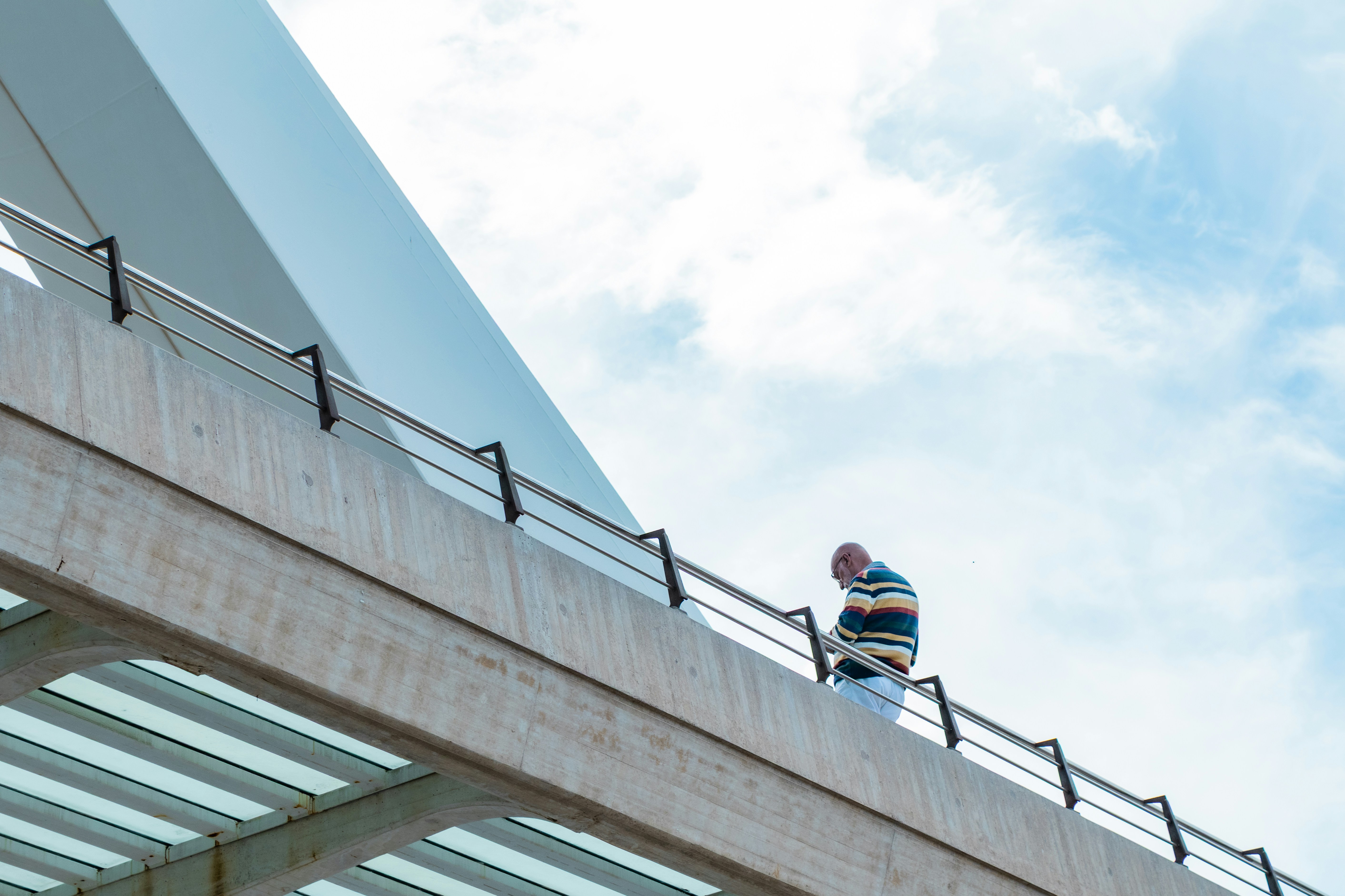 Man standing on a modern bridge under a cloudy sky