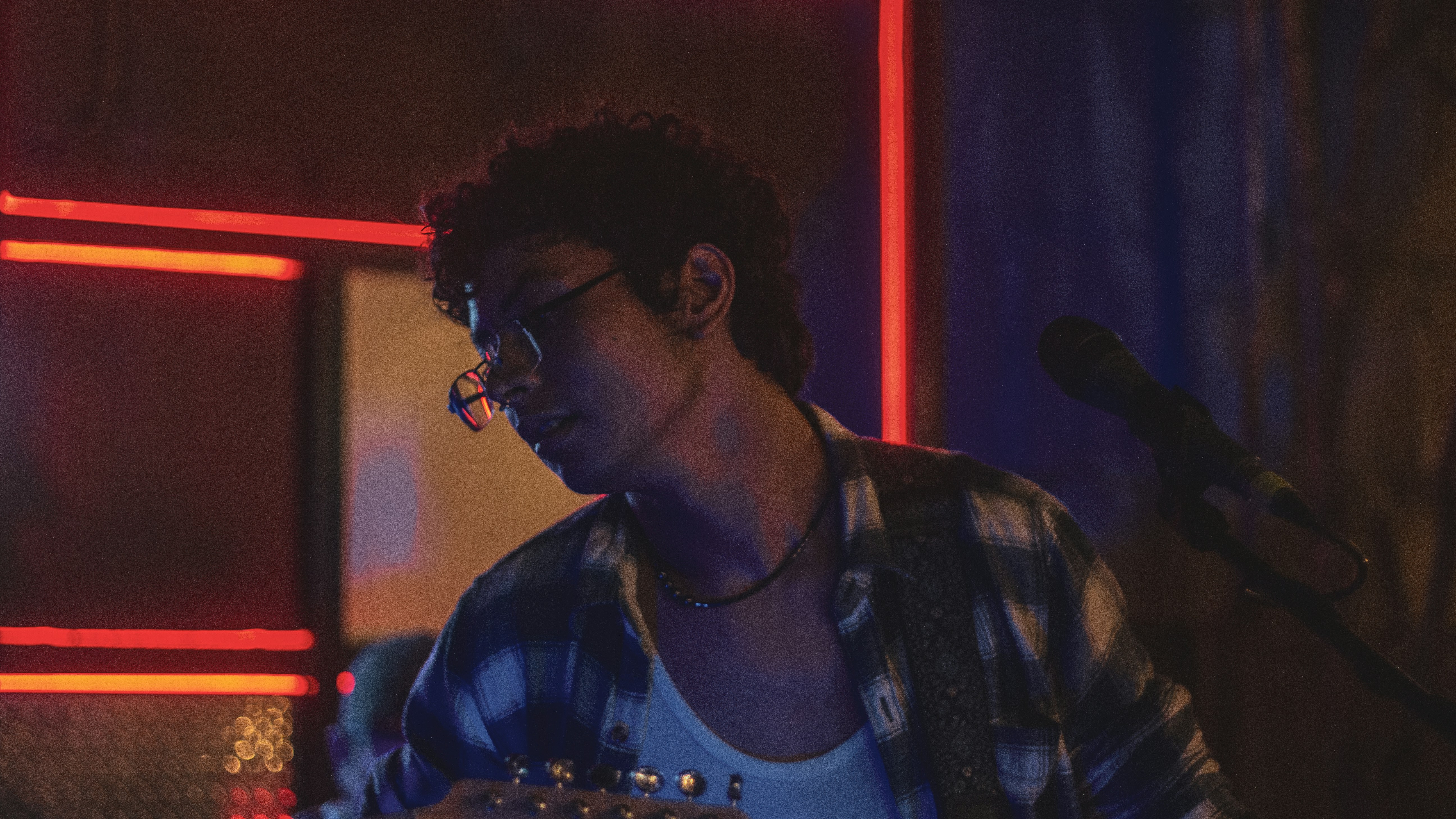 Man playing guitar on stage with neon lights
