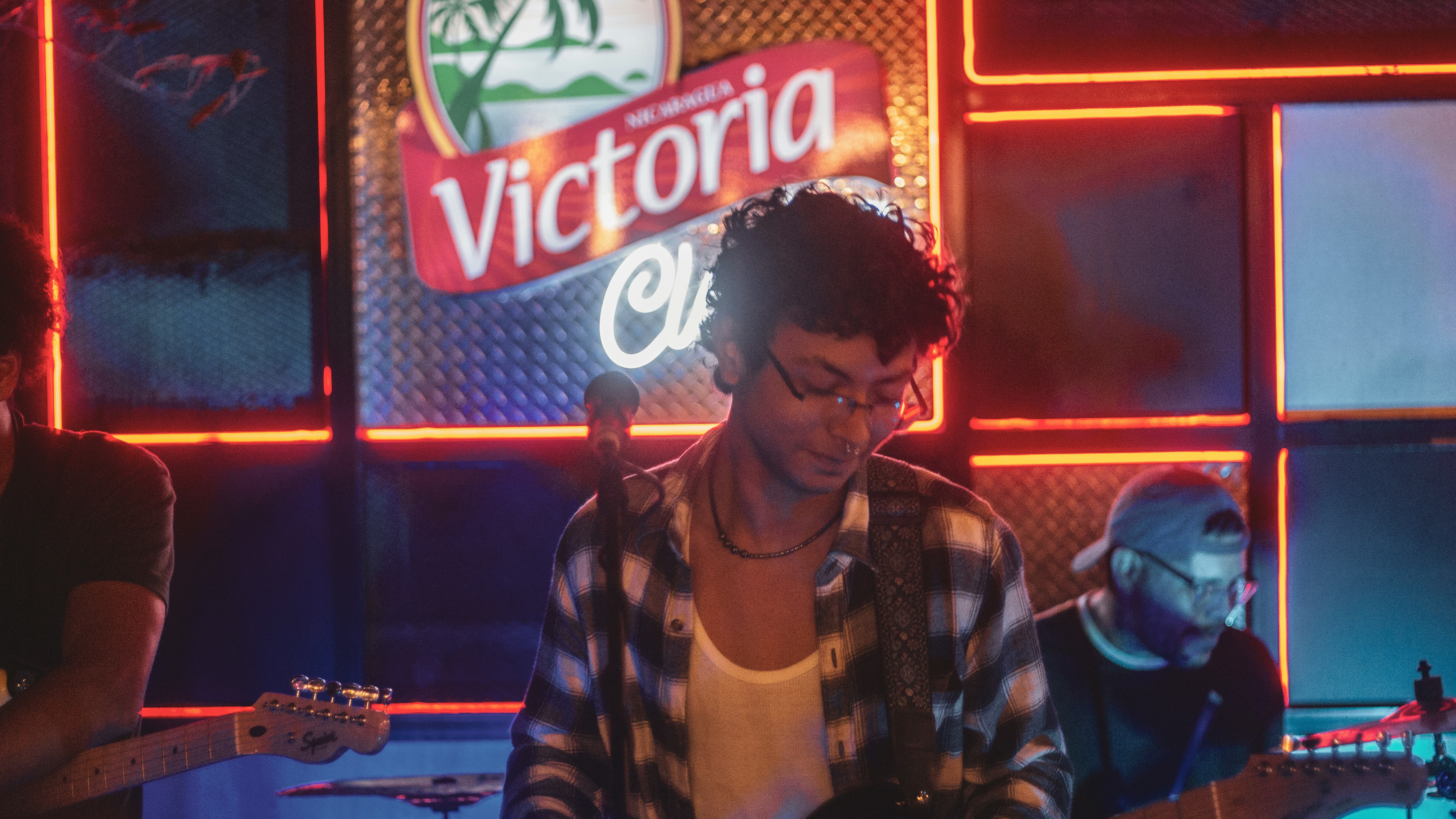 Young man playing guitar in a dimly lit bar. (Photo by Les Taylor on Unsplash)