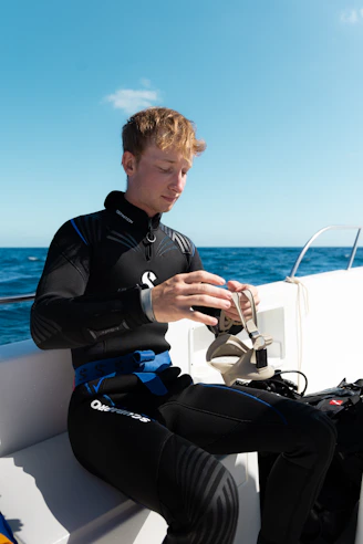 Scuba diver in wetsuit holding mask on boat