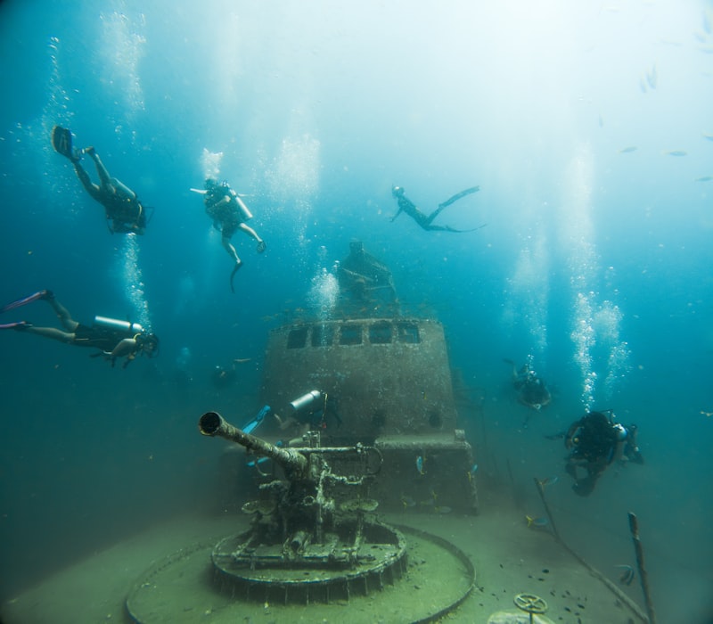 Scuba divers explore a sunken shipwreck with a cannon.