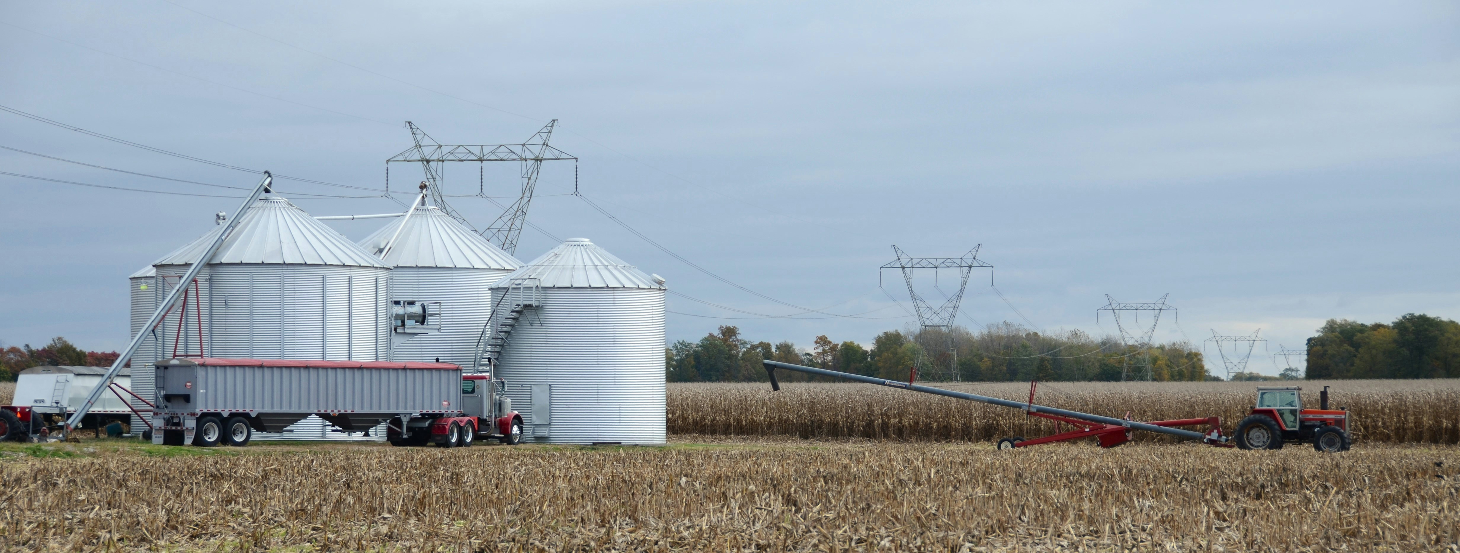 Getreidesilos und landwirtschaftliche Geräte auf einem abgeernteten Feld.