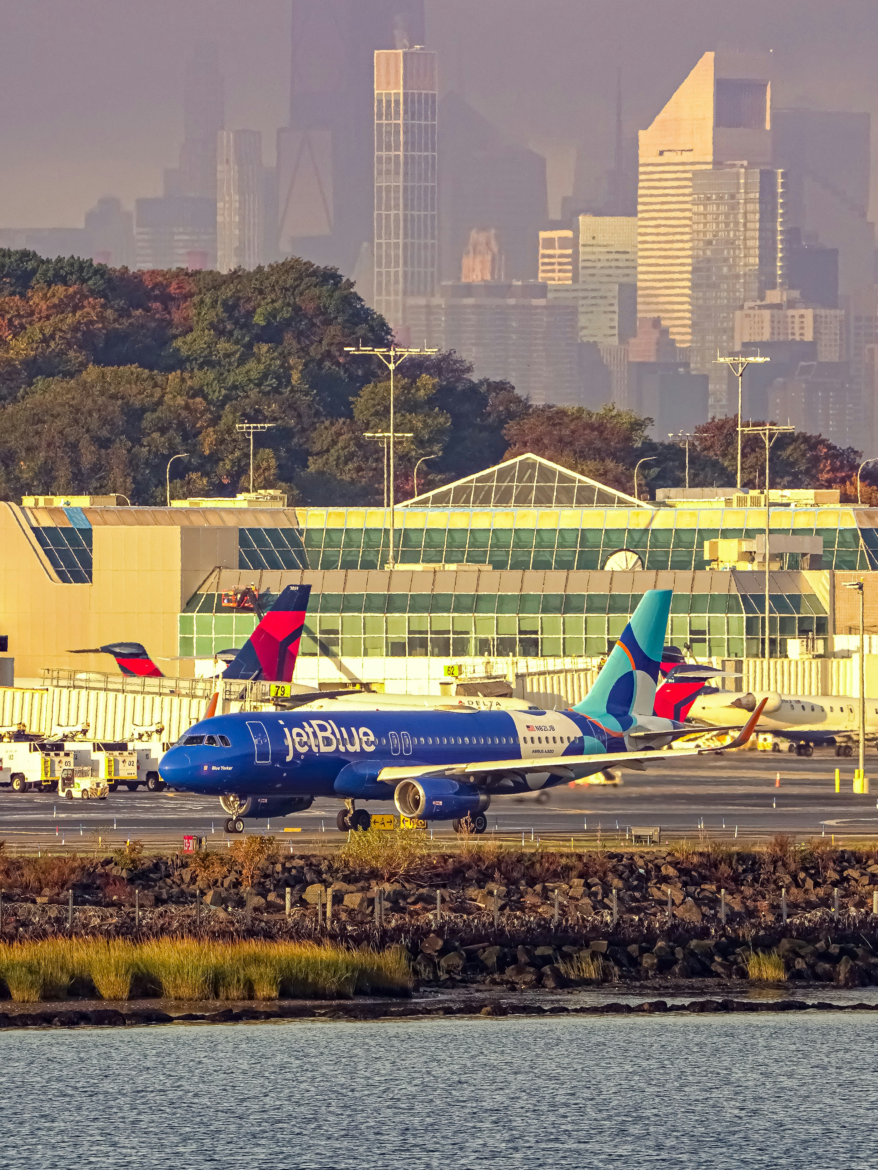 Jetblue airplane at an airport with city skyline.