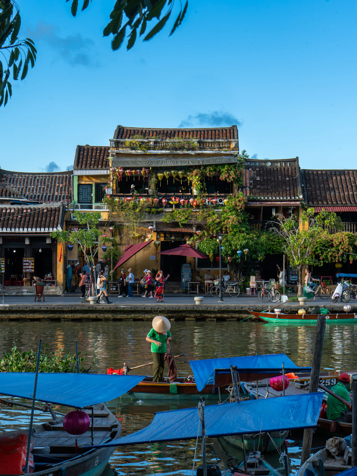 Boats moored along a canal lined with yellow colonial buildings in Hoi An Ancient Town, Vietnam