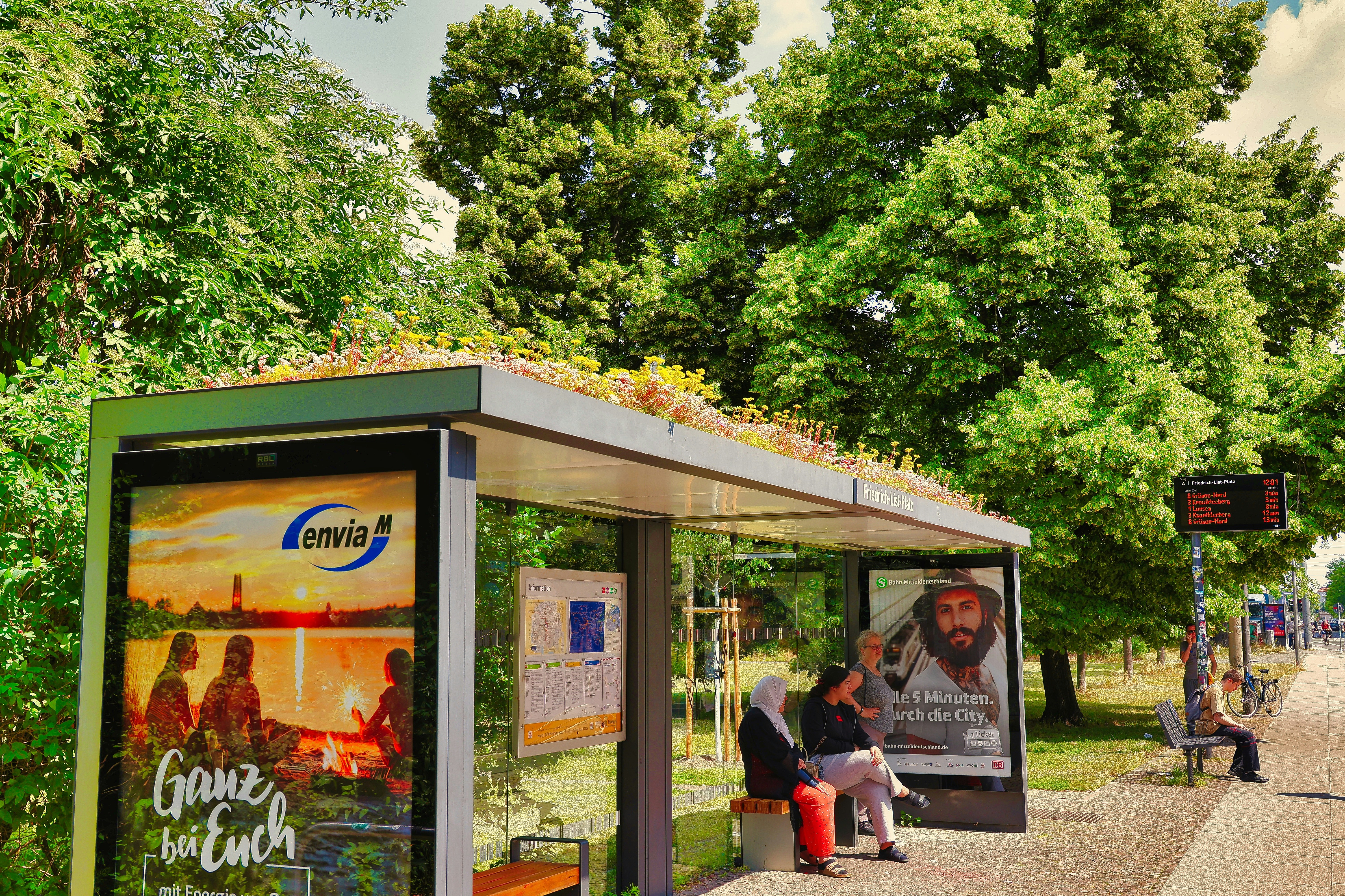 People waiting at a bus stop with green roof.