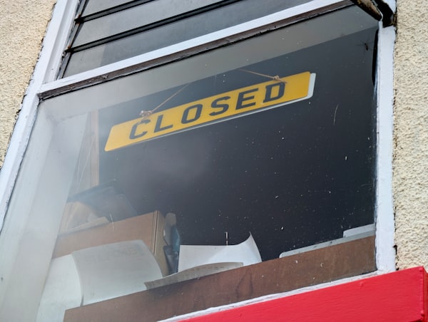 Yellow CLOSED sign hanging in a dusty shop window