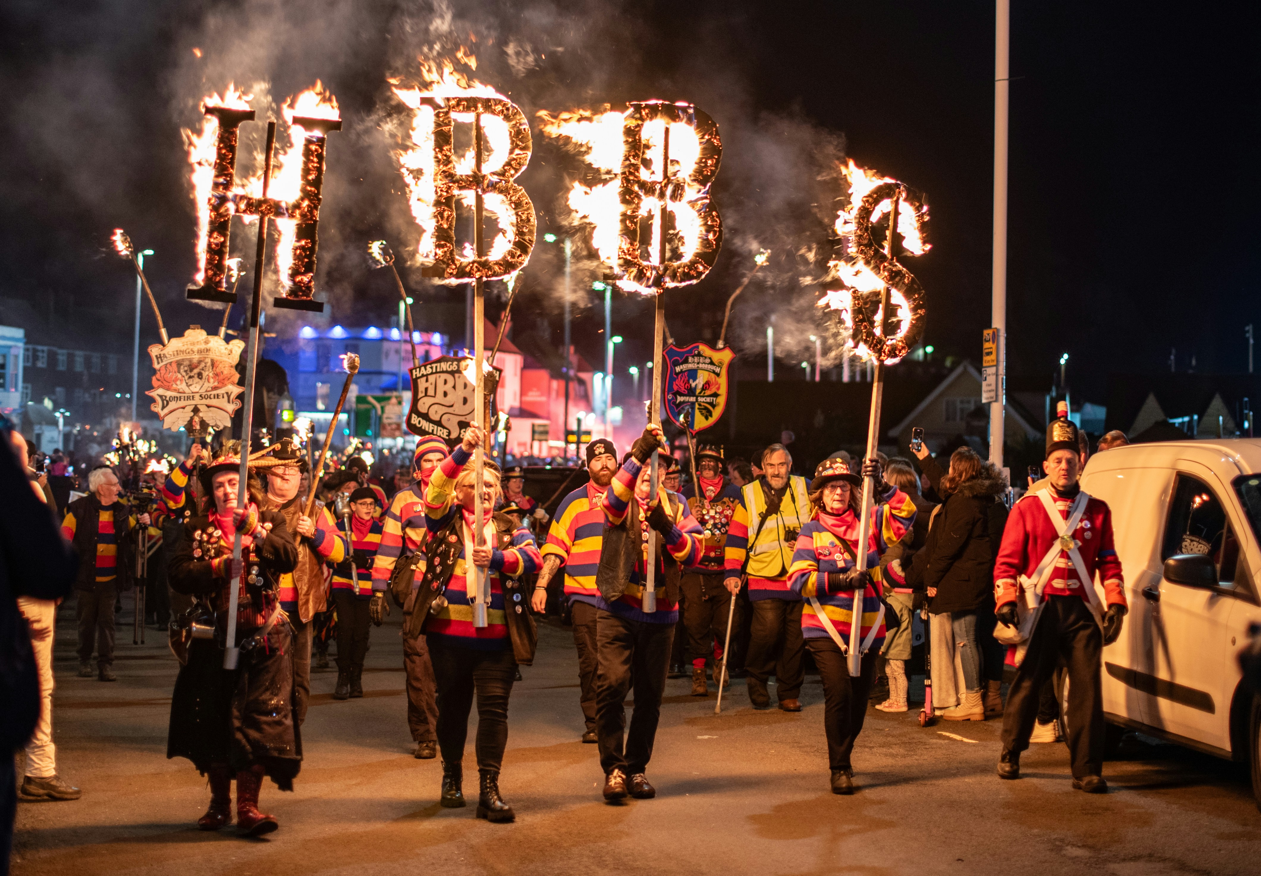 People carrying flaming letters in a nighttime parade