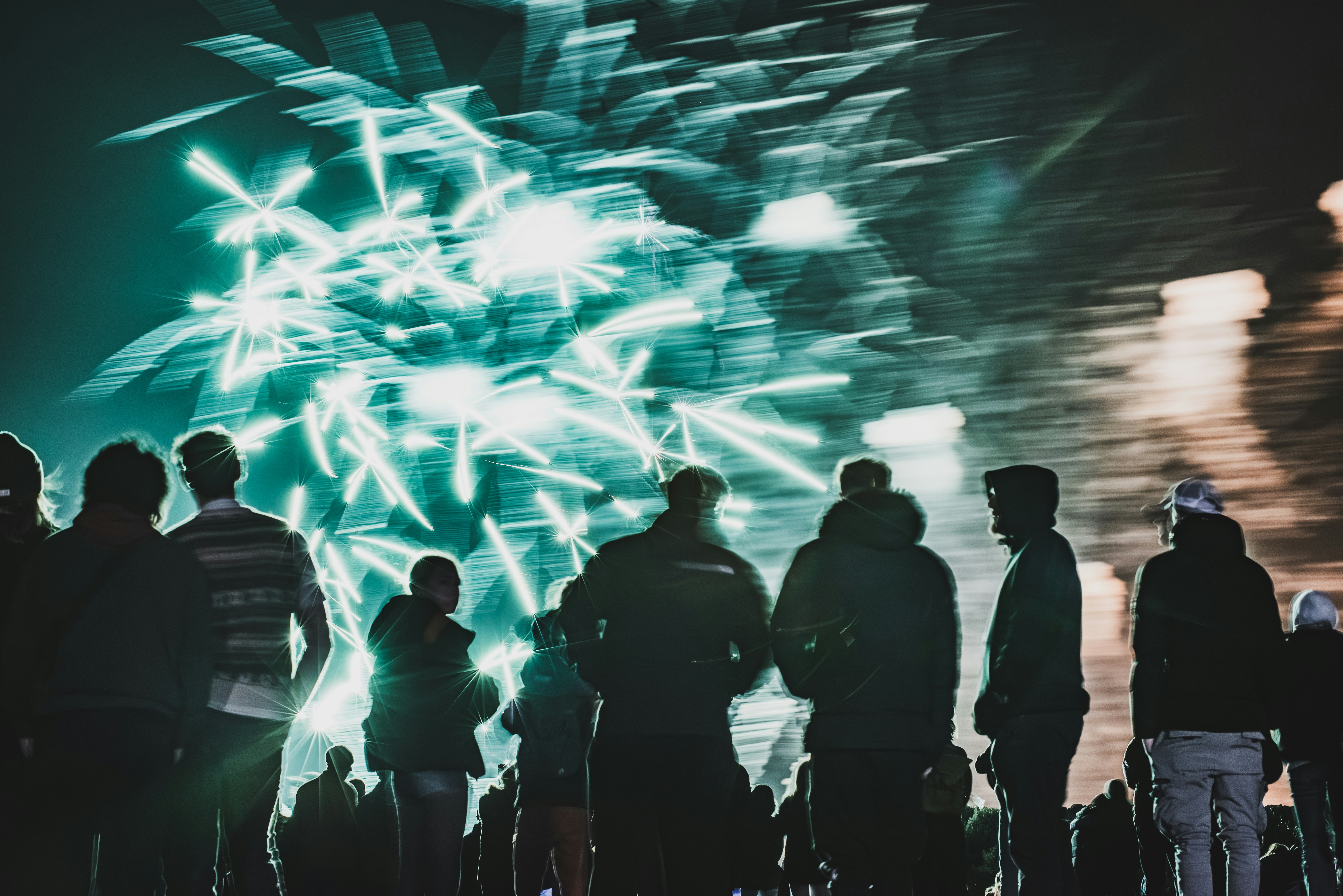 Silhouetted crowd watches bright fireworks display