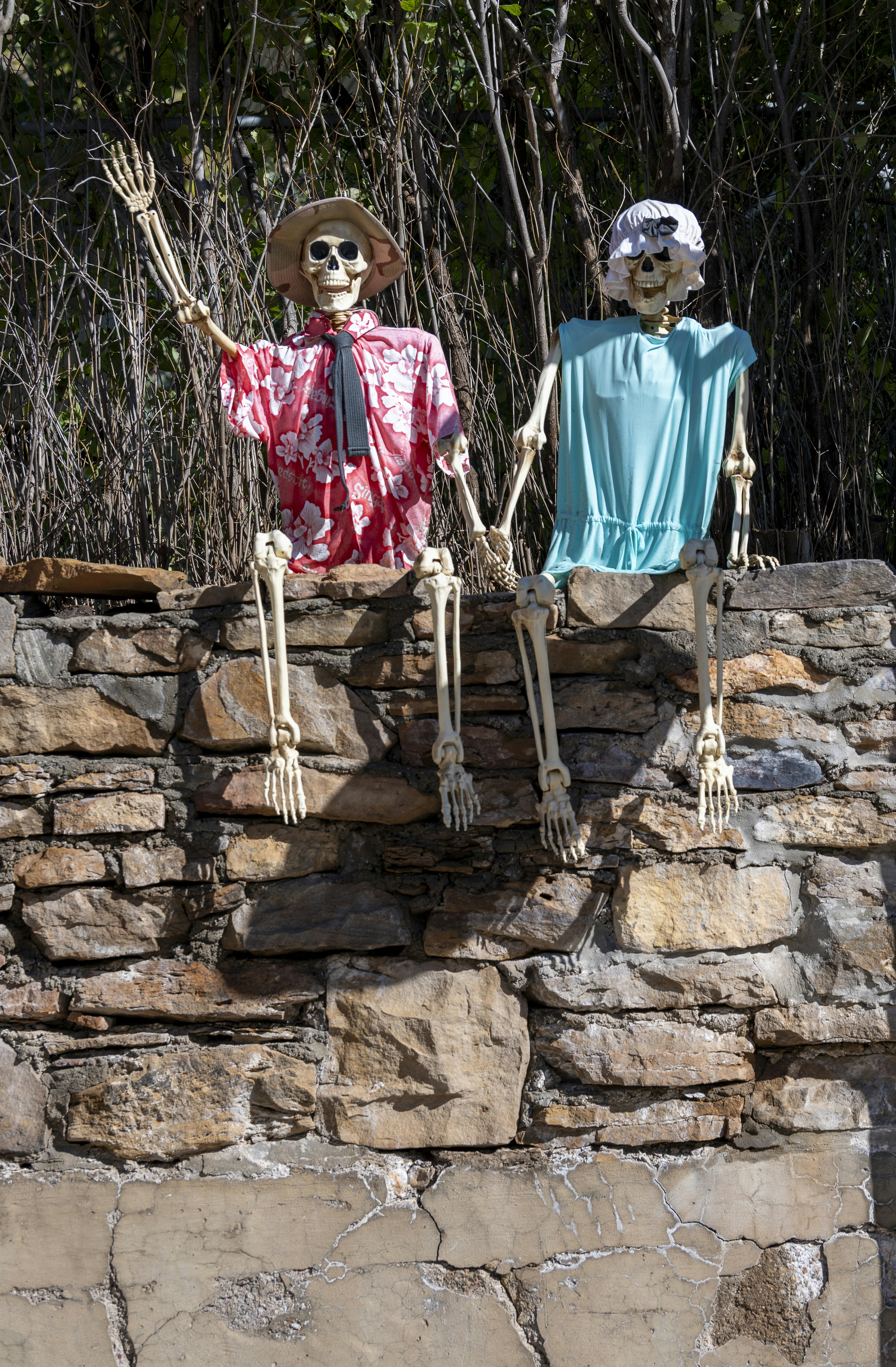 Zwei Skelette in Kleidern sitzen an einer Wand.