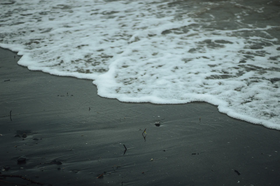 Serene beach scene with waves crashing onto the shoreline under an overcast sky