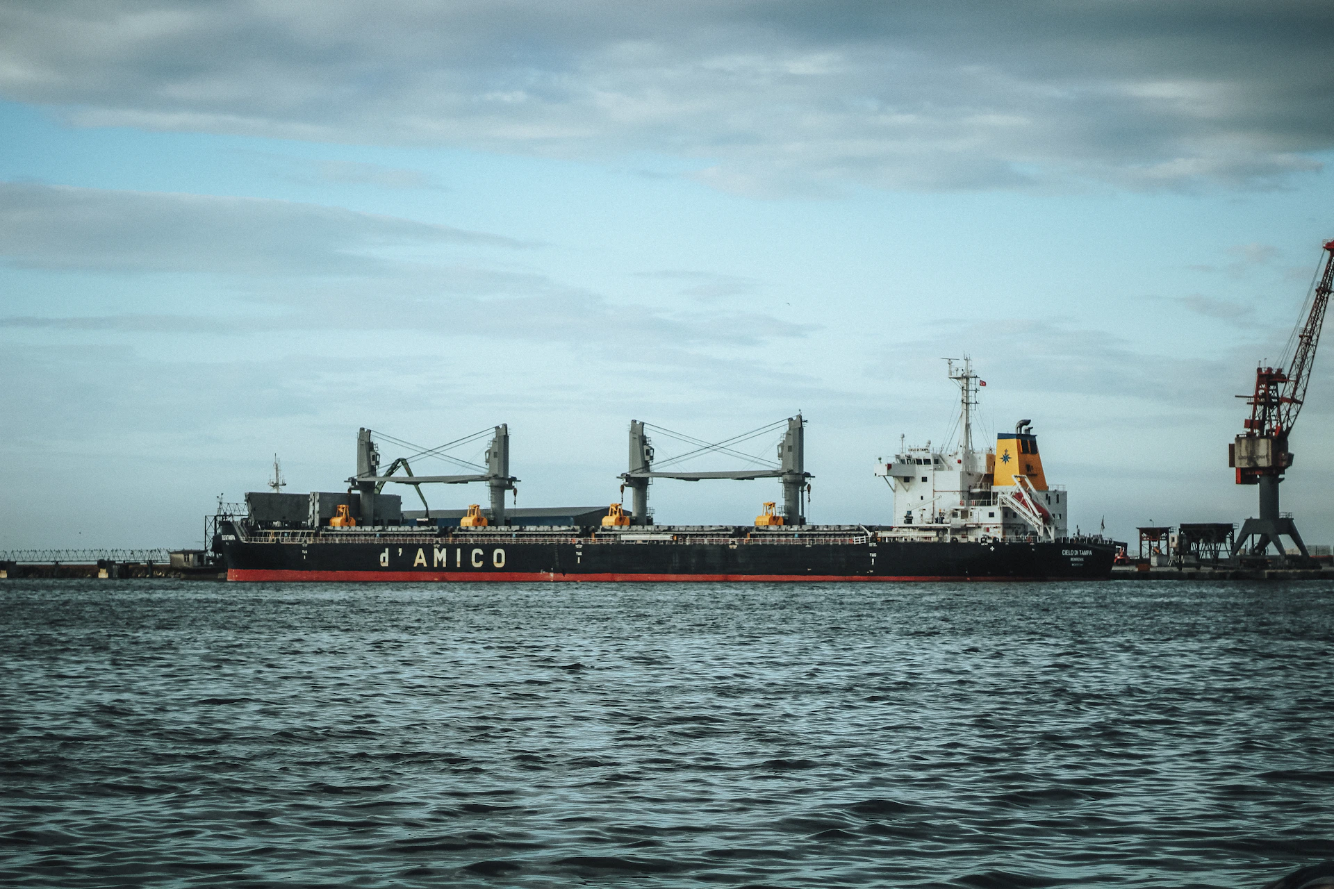 Large cargo ship docked at a harbor with a crane