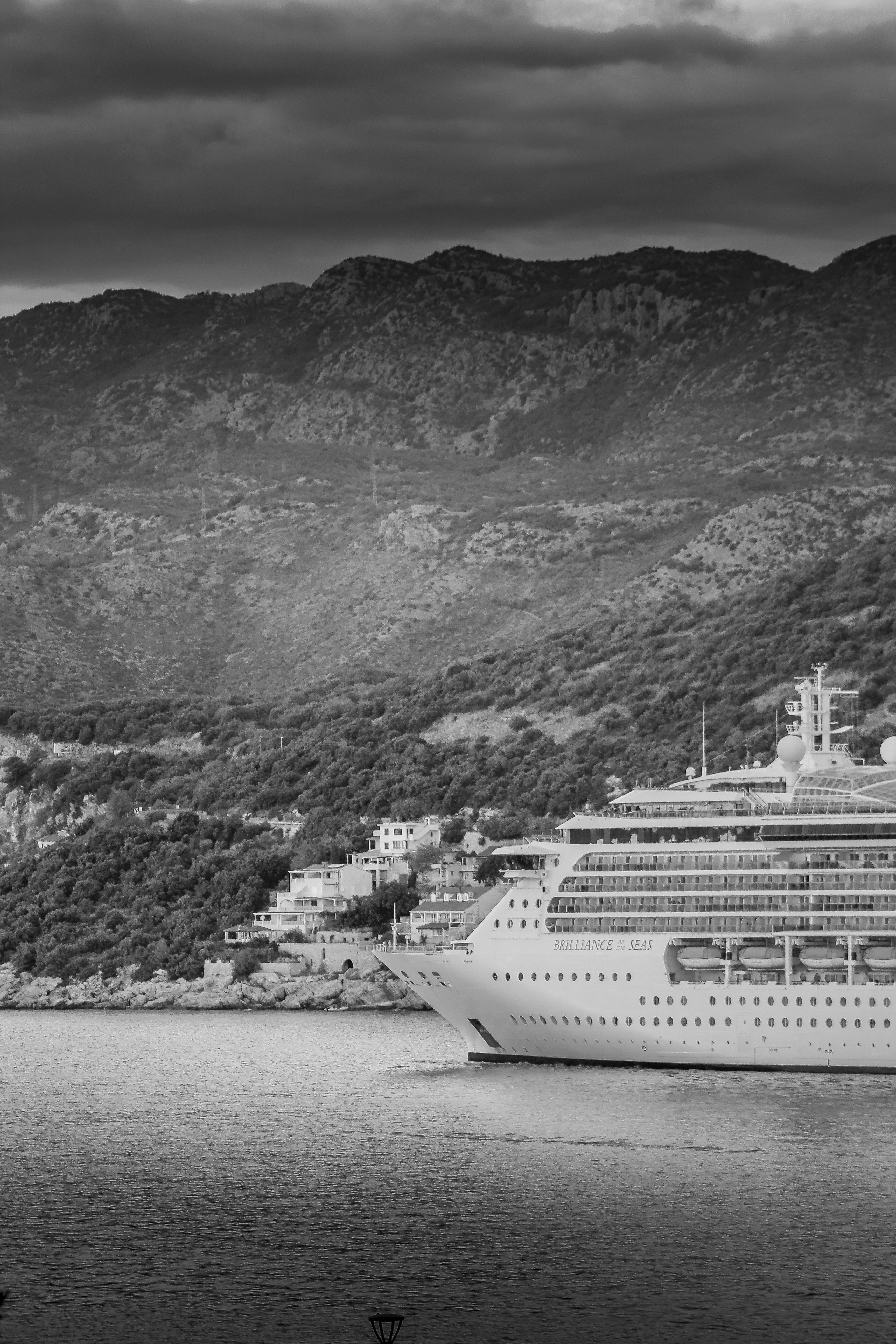 Large cruise ship sails near a mountainous coastline.